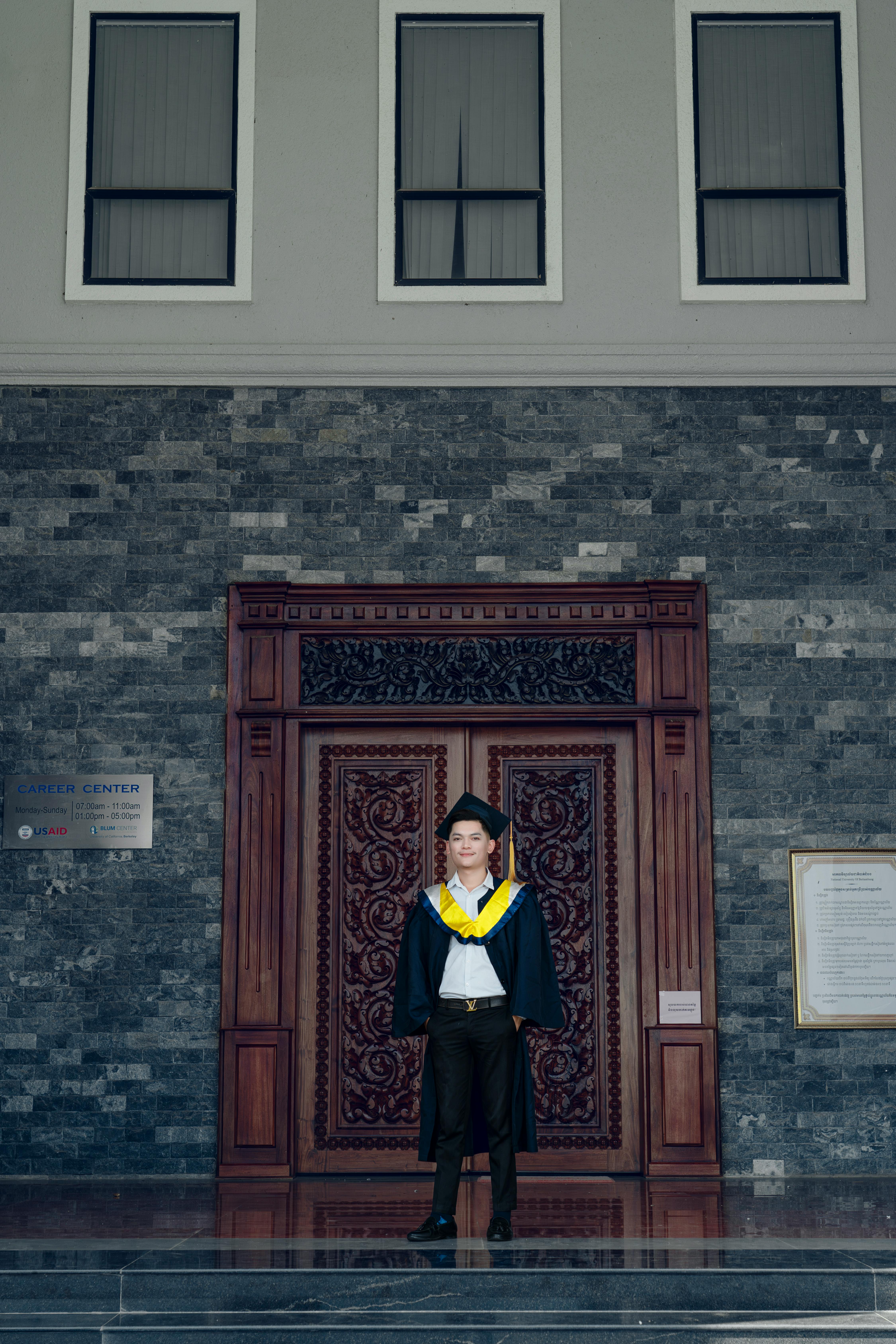 a man in a graduation gown standing in front of a door