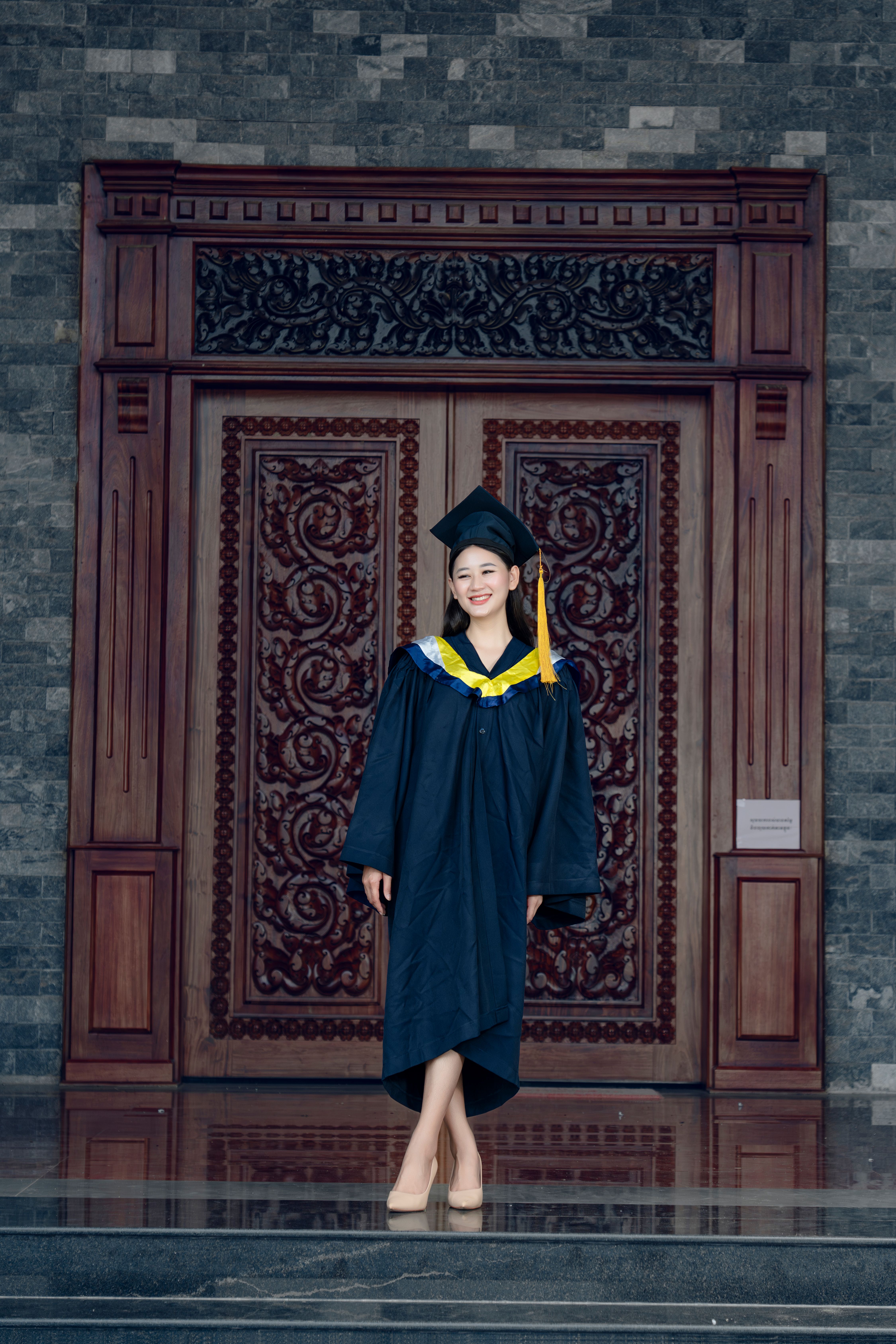 A woman in a graduation gown standing in front of a door · Free Stock Photo