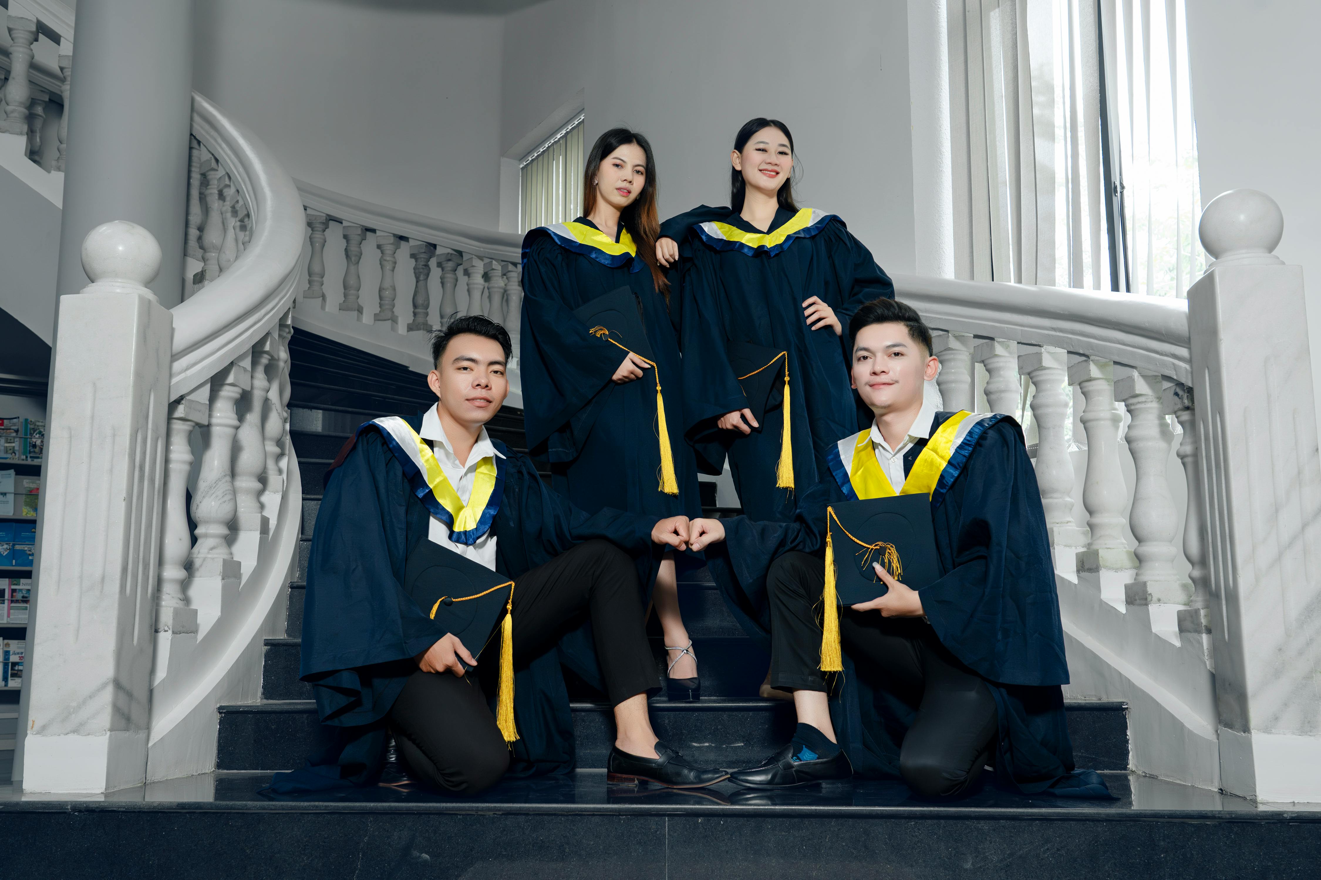 four graduates posing for a photo on stairs