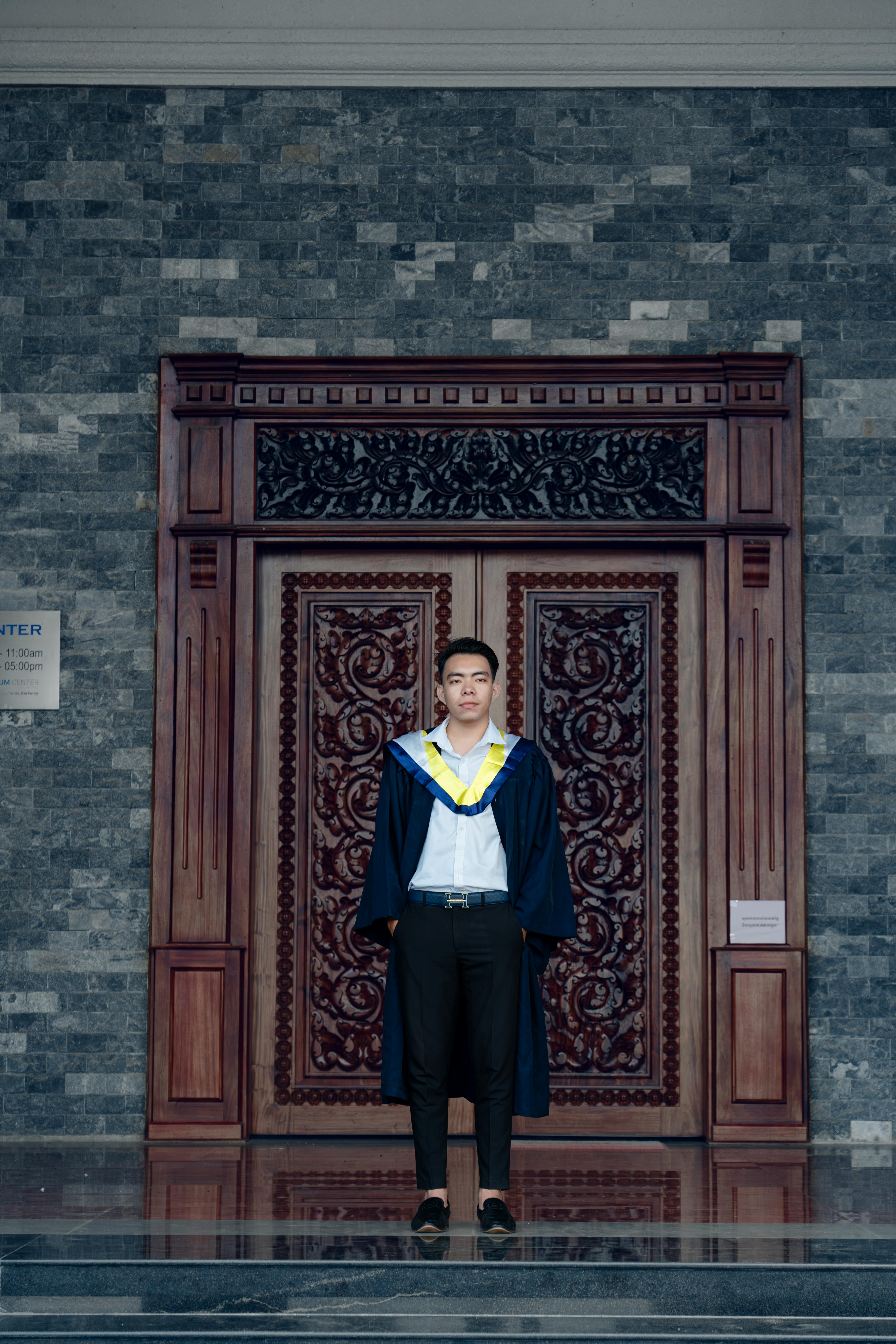 a man in a graduation gown standing in front of a door