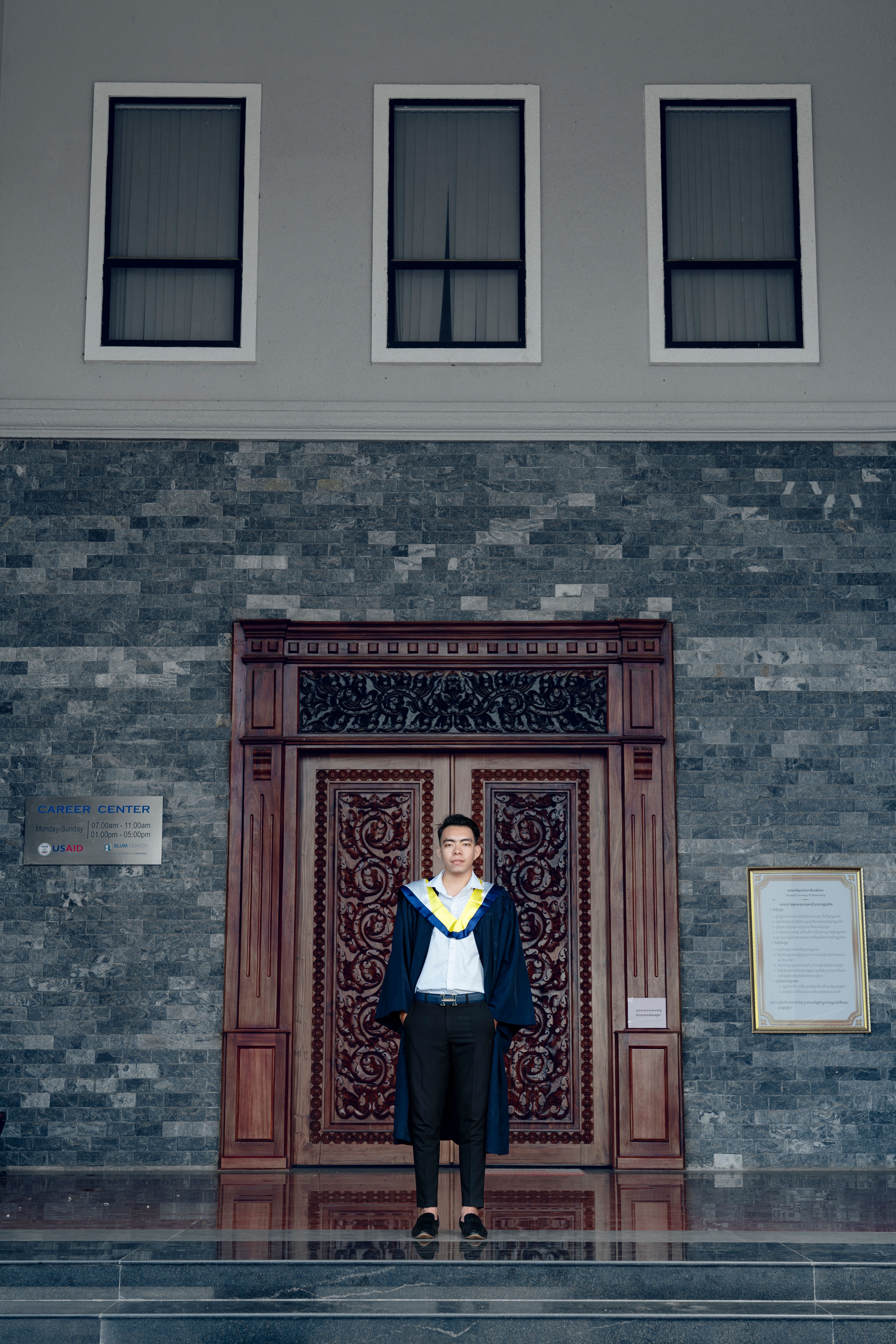 A man in a graduation gown standing in front of a door · Free Stock Photo