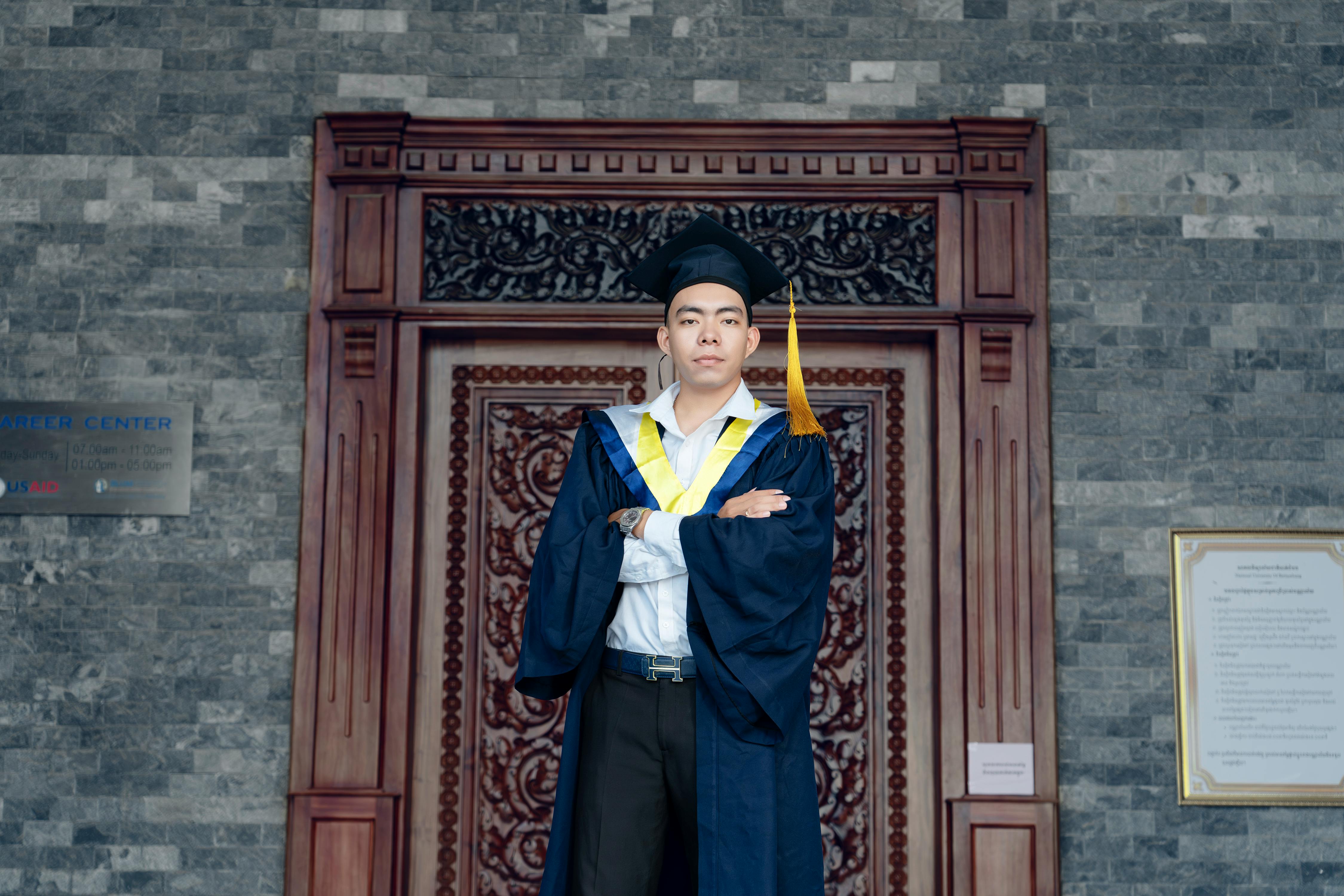 a man in a graduation gown standing in front of a door