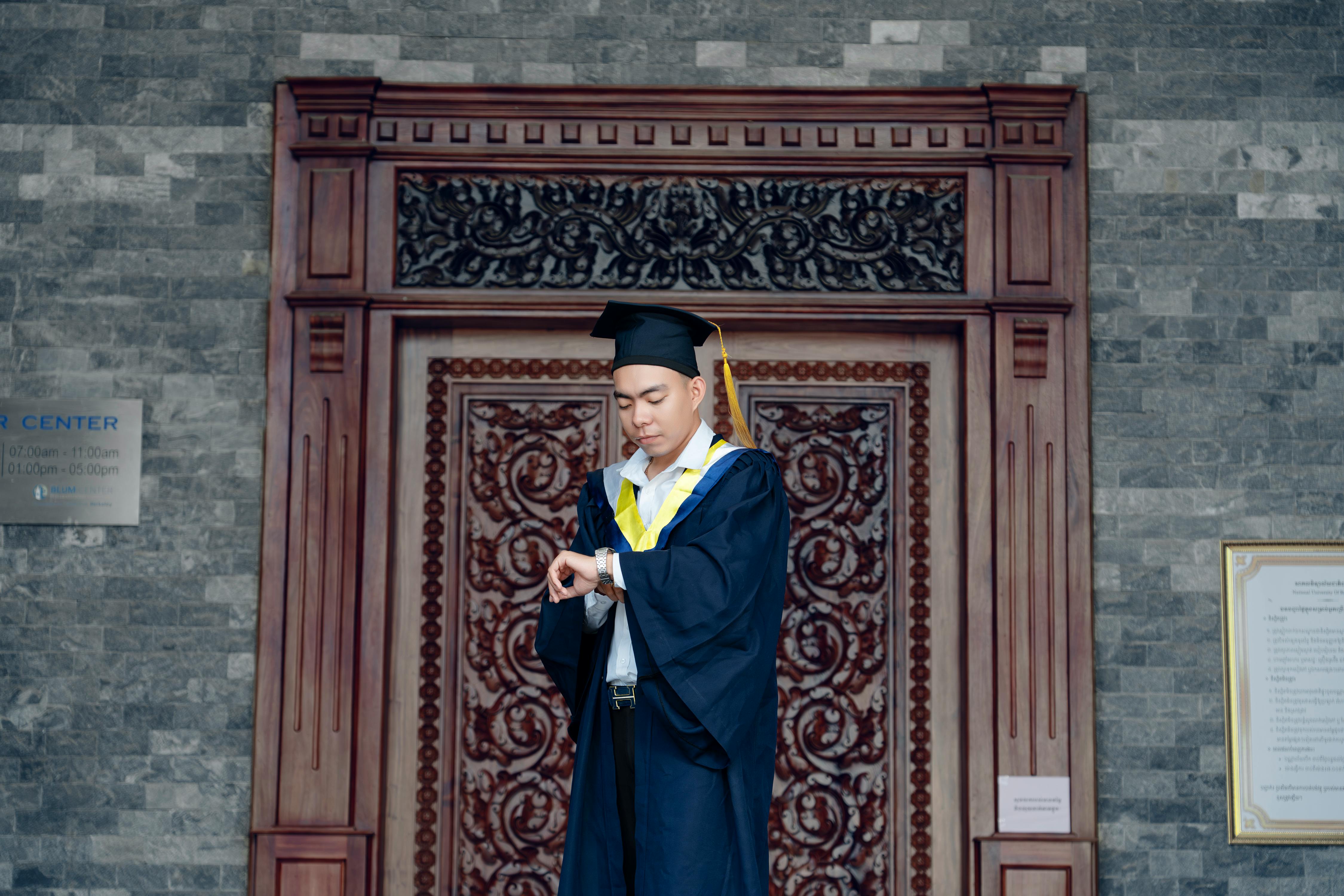 a man in a graduation gown is standing in front of a door