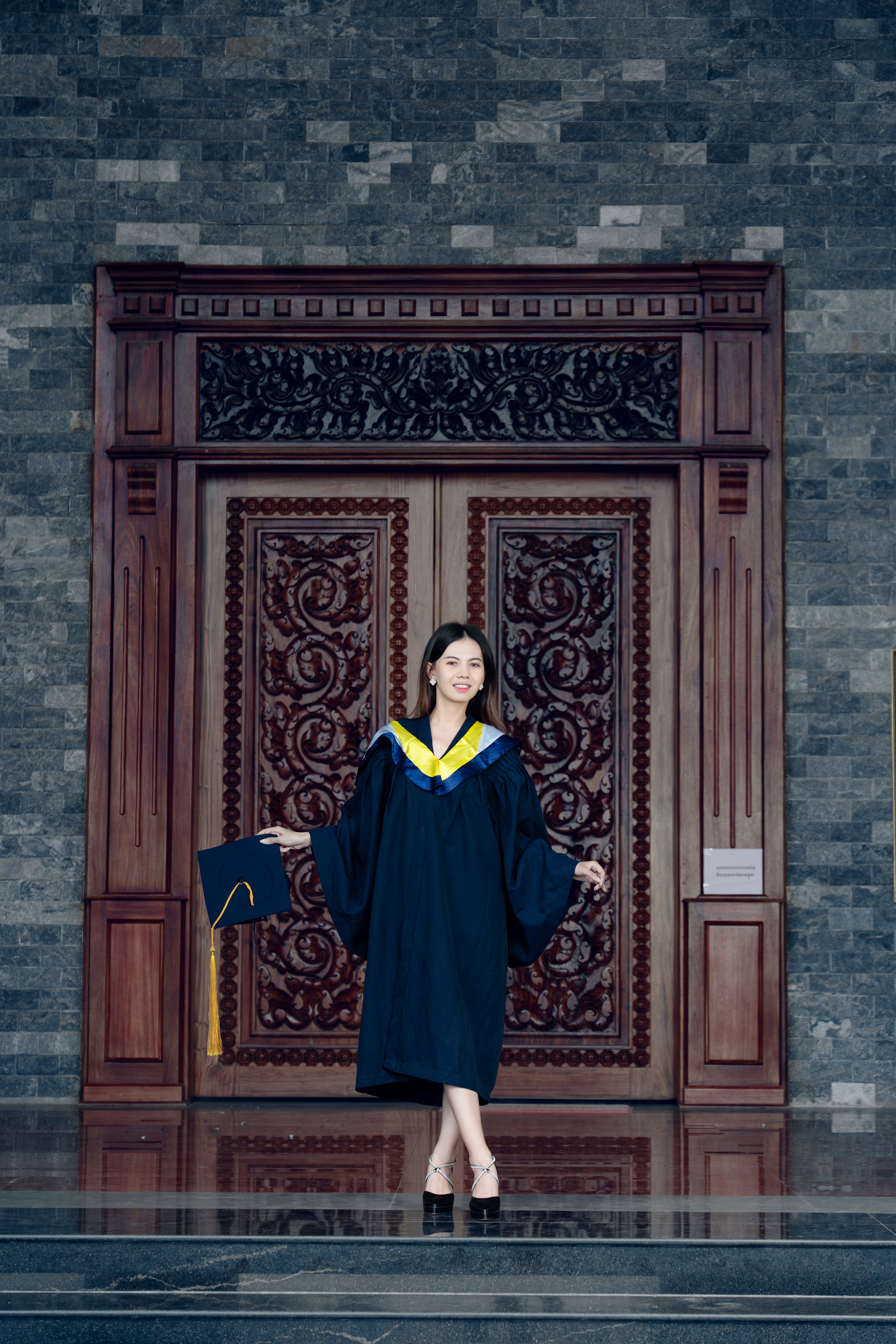 A woman in a graduation gown standing in front of a door · Free Stock Photo