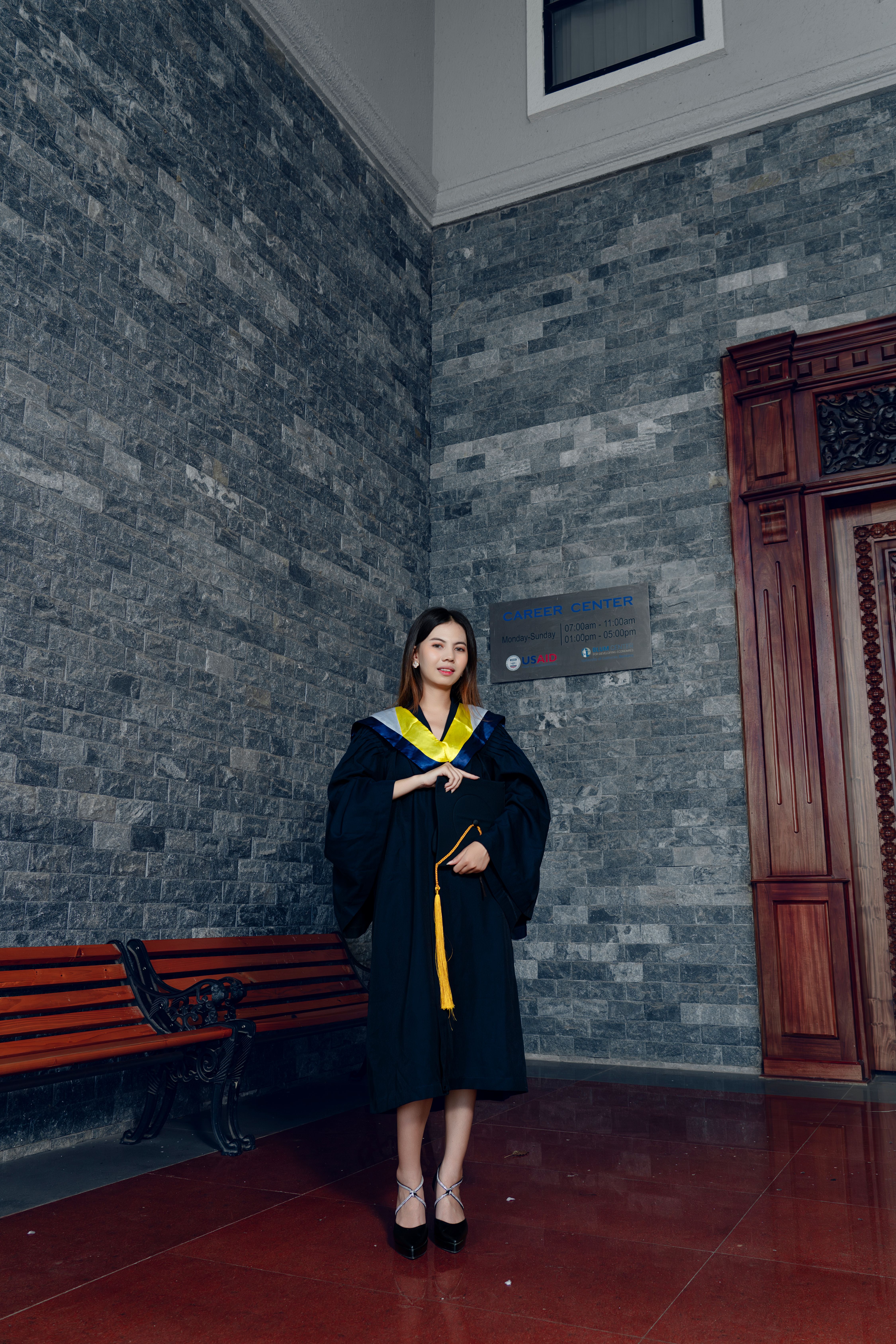 A woman in a graduation gown standing in front of a brick wall · Free ...