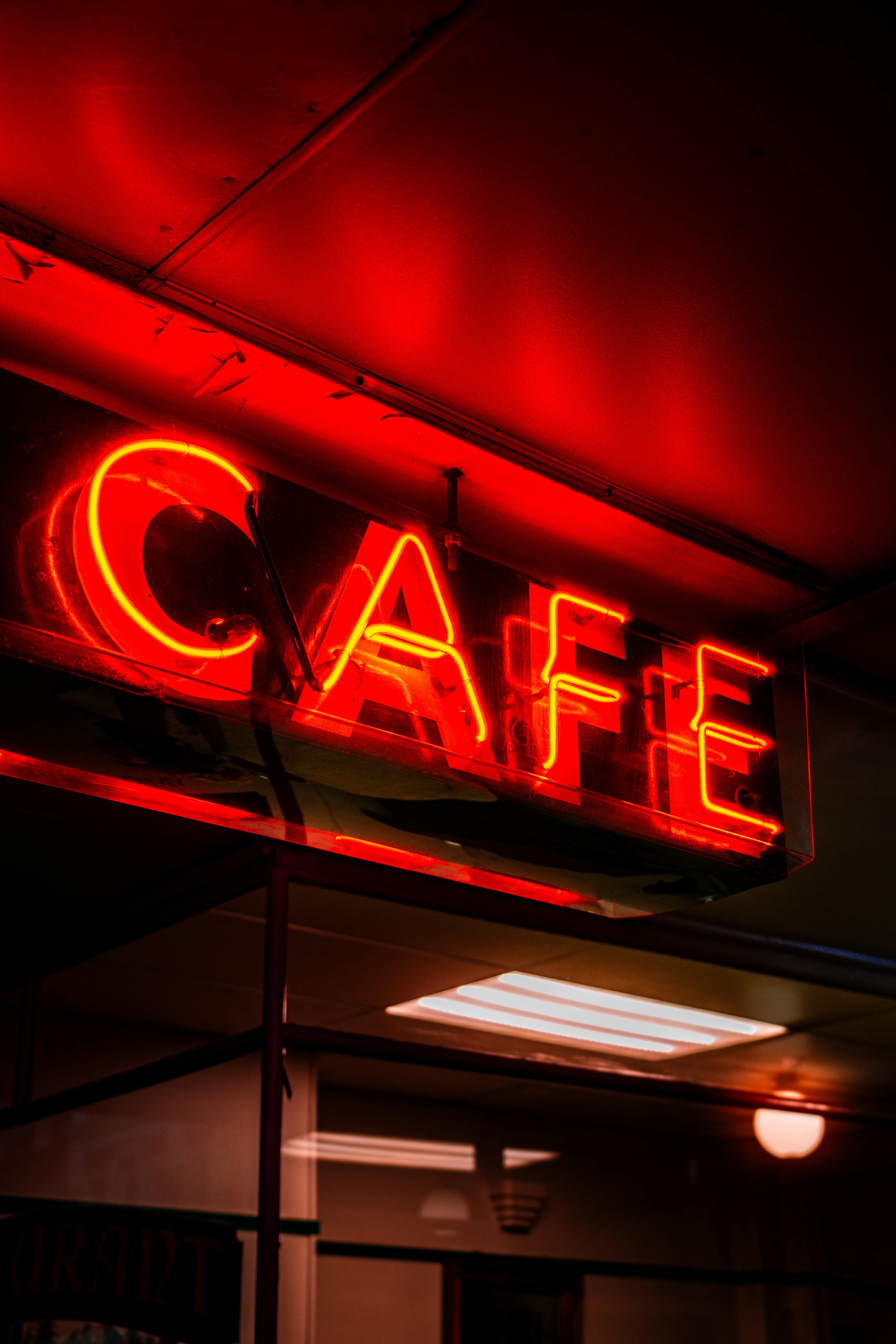 Bright red neon sign displaying the word 'CAFE' glowing in the evening interior setting.