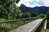 一座风景优美的木桥，坐落在绿意盎然、山峦高耸的背景之中，非常适合旅行和自然主题