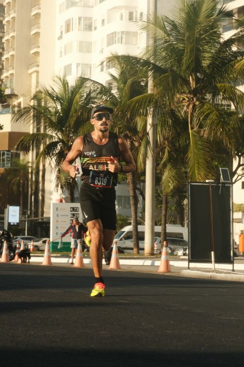 Free Man running in marathon event in Rio de Janeiro amid cityscape and palm trees. Stock Photo