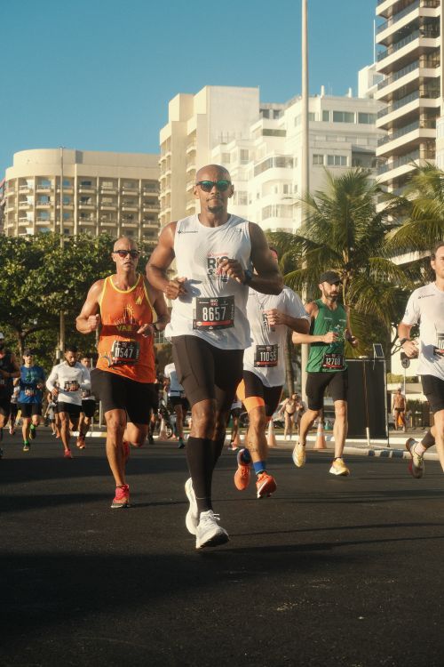 Free Athletes running a marathon on Rio de Janeiro streets on a sunny day, showing determination and endurance. Stock Photo