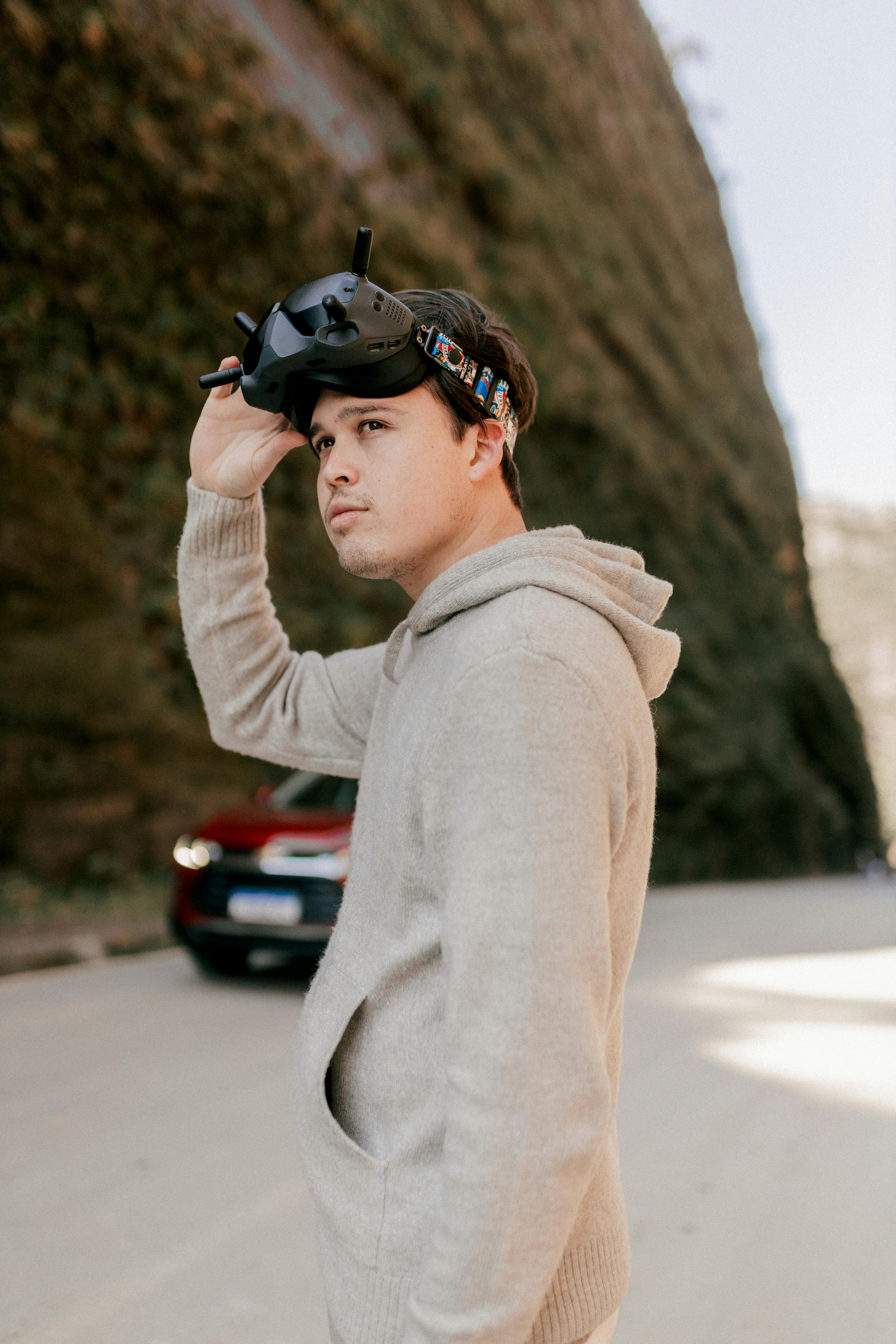 A man wearing a hoodie and holding a virtual reality headset