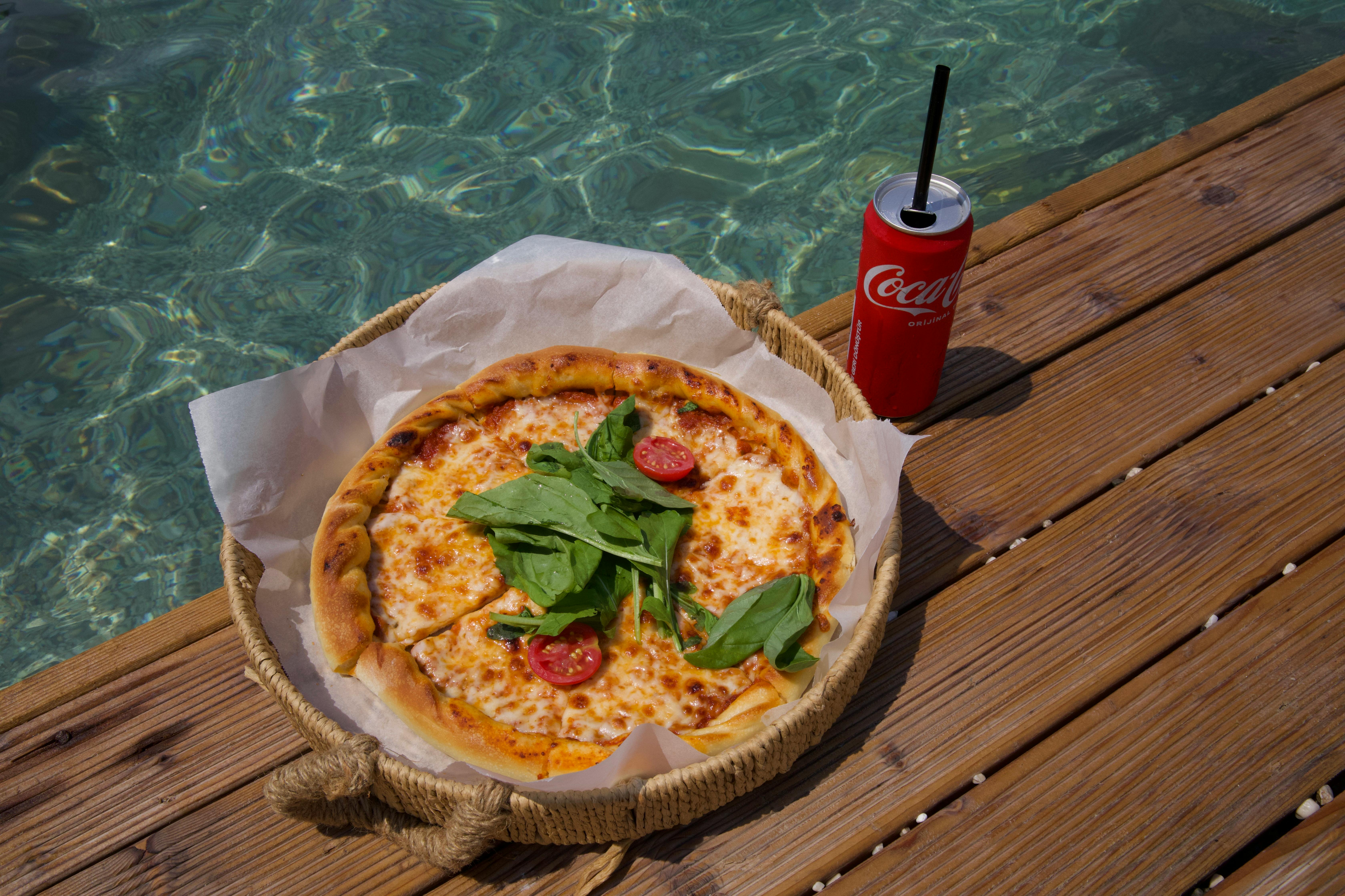 a pizza on a wooden table next to a drink