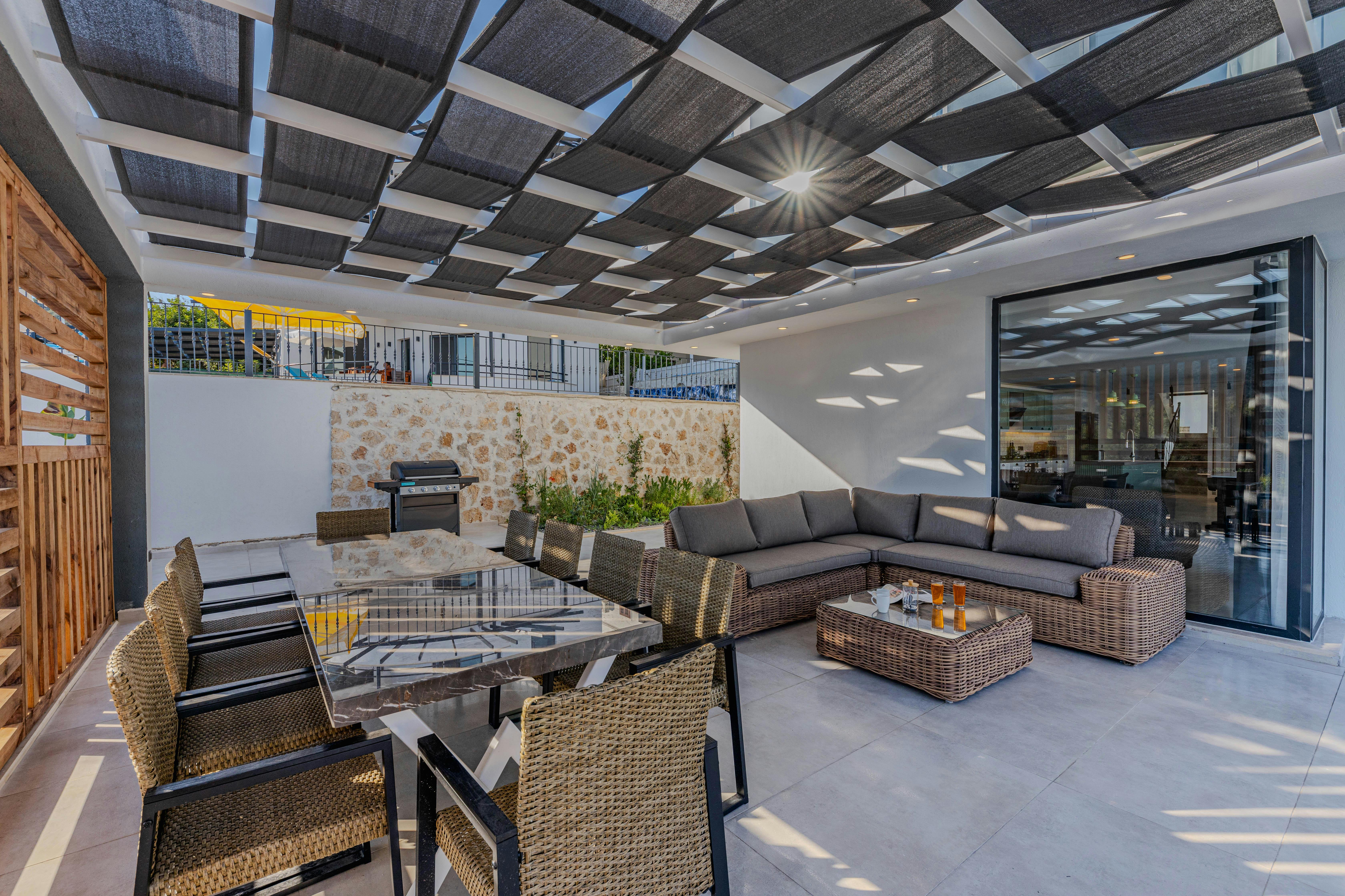 Moderne Terrasse mit grauem Aluminiumdach, Glasfeldern und Esstisch vor Putzfassade