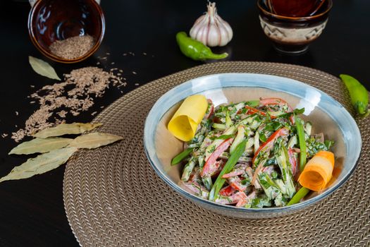 A colorful veggie salad with herbs on a woven mat, featuring peppers and spices.