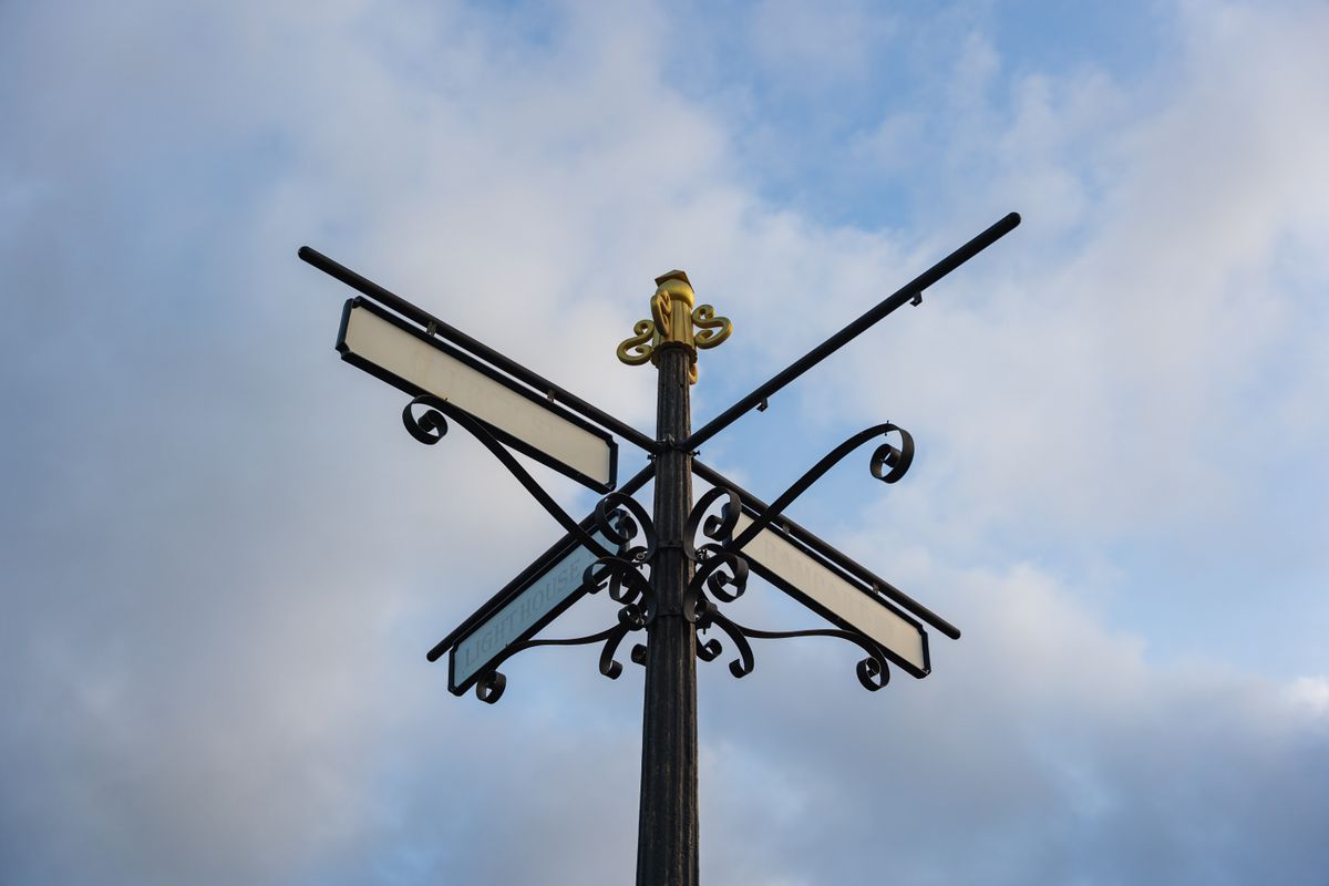 Ornate vintage signpost pointing in several directions against a blue sky in Galle, Sri Lanka