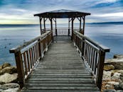 木板路上的木制凉亭一直延伸到平静的湖边，湖中有鸭子和岩石岸