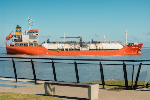 A red cargo ship passes through the harbor in Porto Alegre under a clear blue sky.
