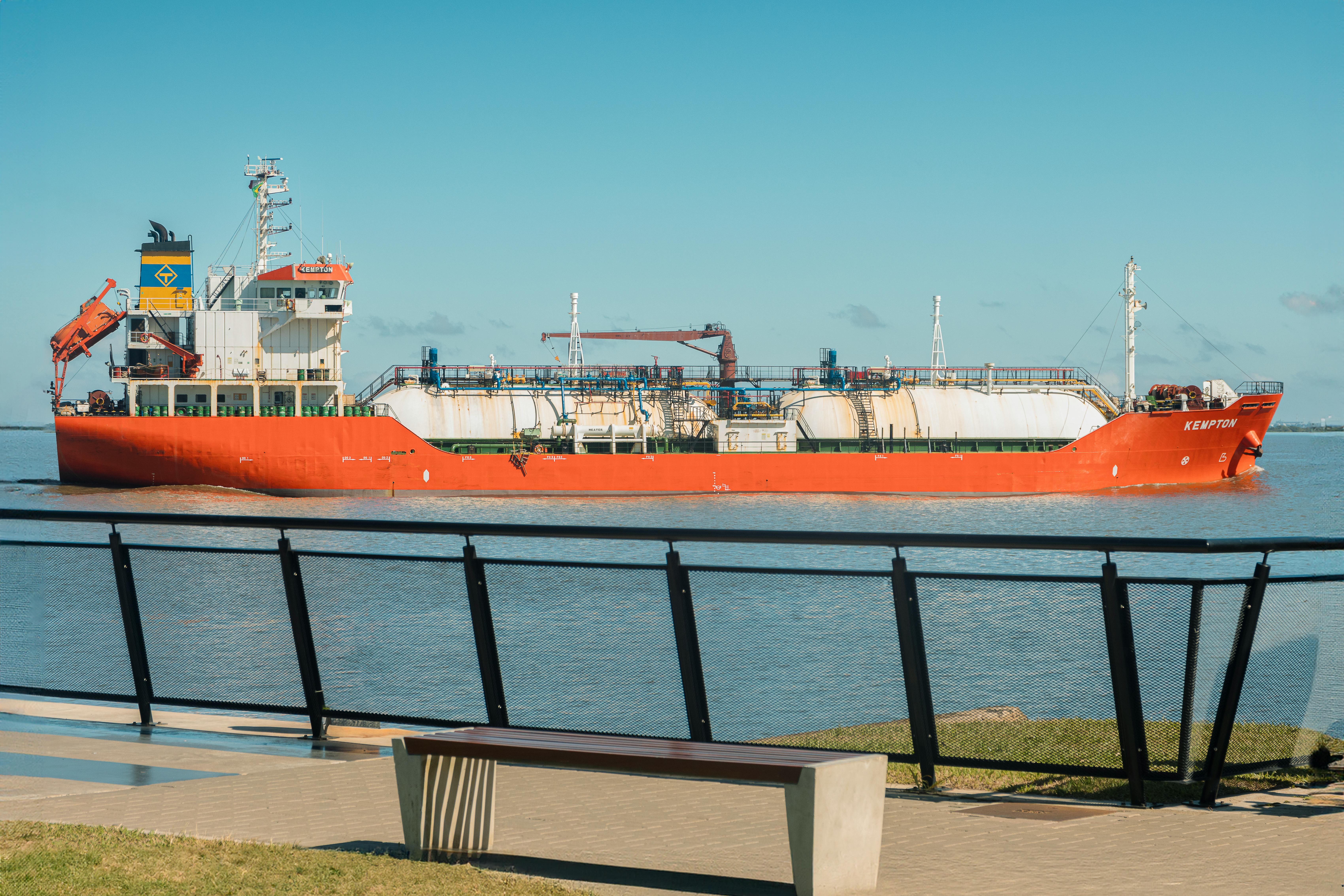 Free A red cargo ship passes through the harbor in Porto Alegre under a clear blue sky. Stock Photo