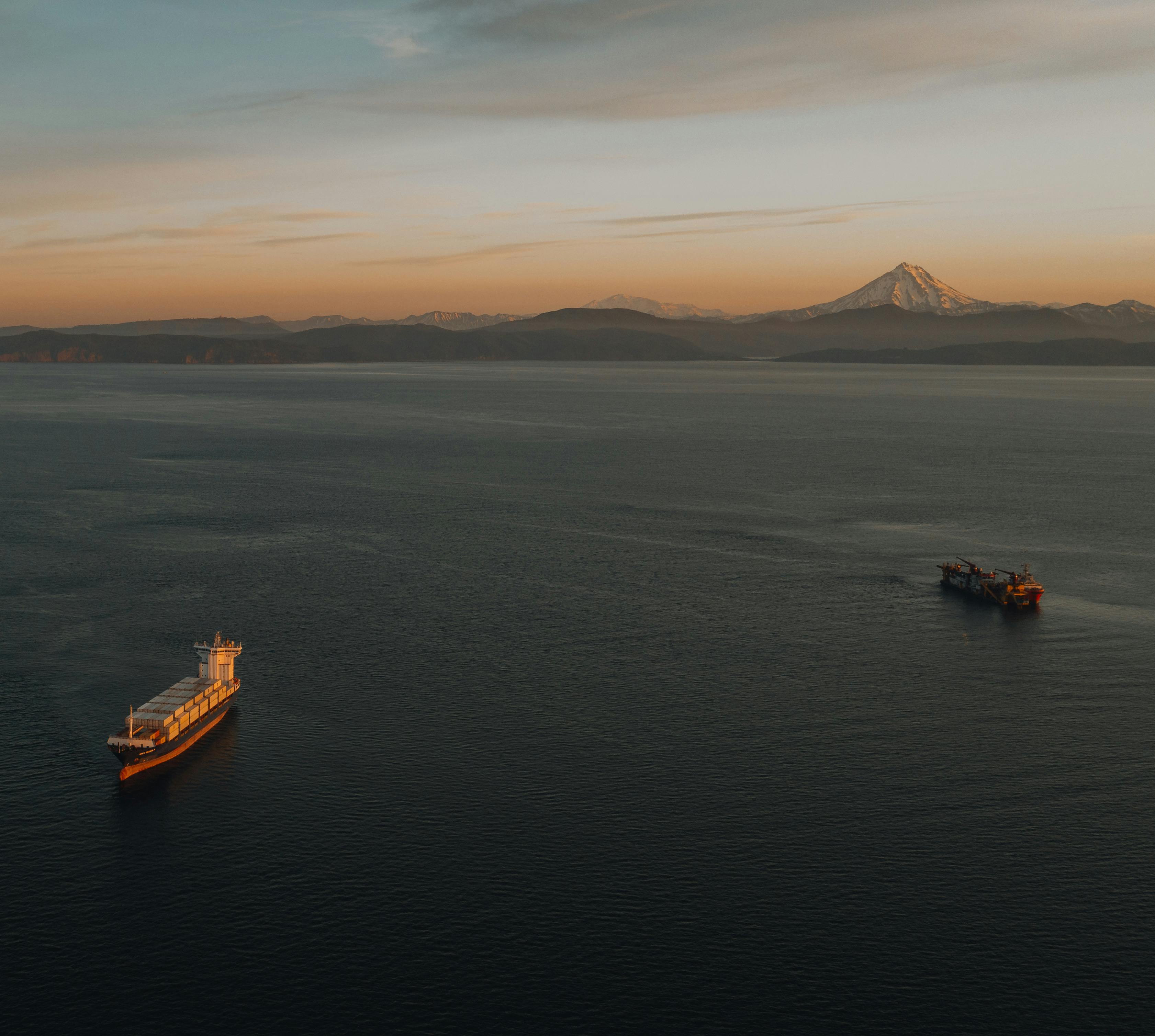 two ships are in the ocean near a mountain