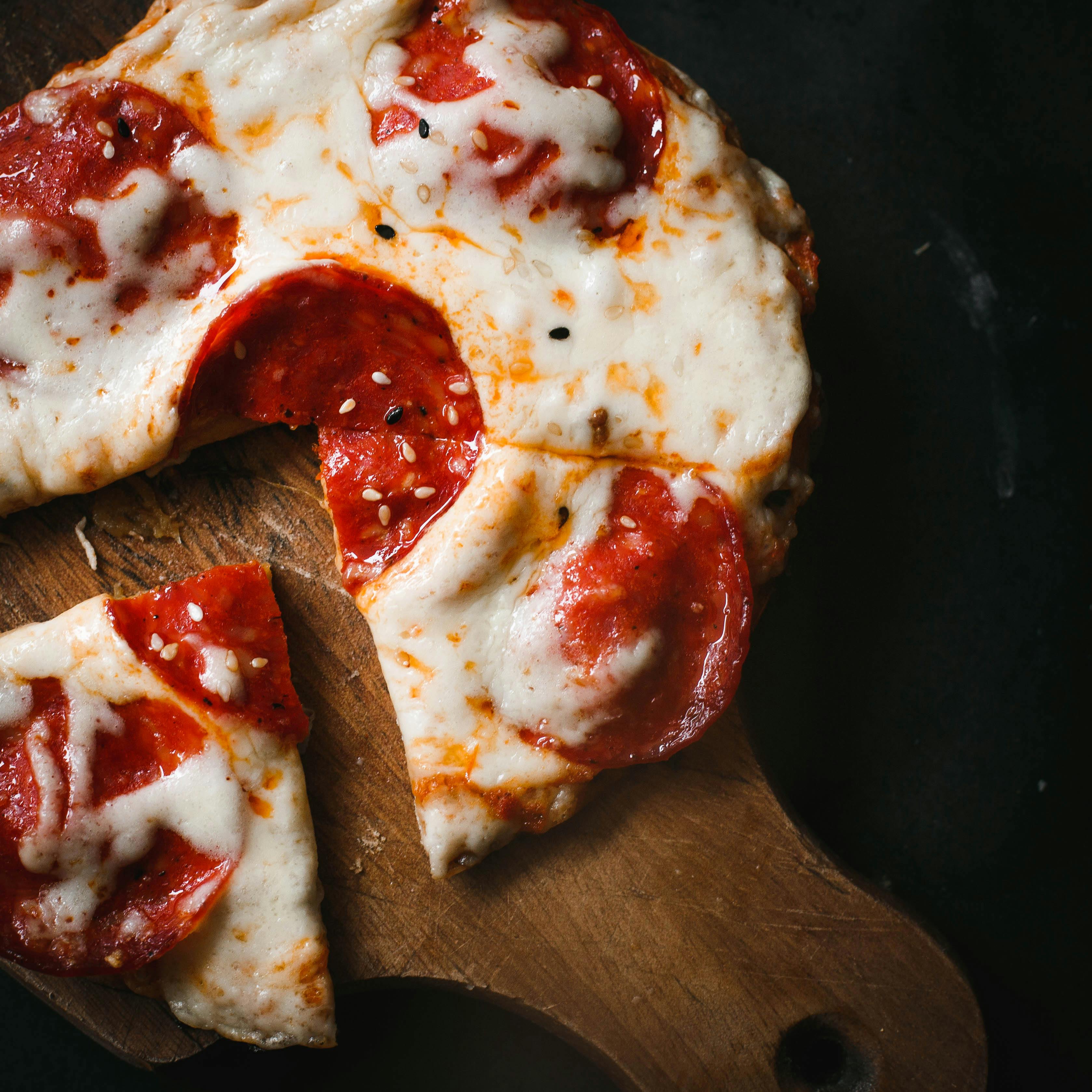 A mouthwatering pepperoni pizza slice on a rustic wooden board.