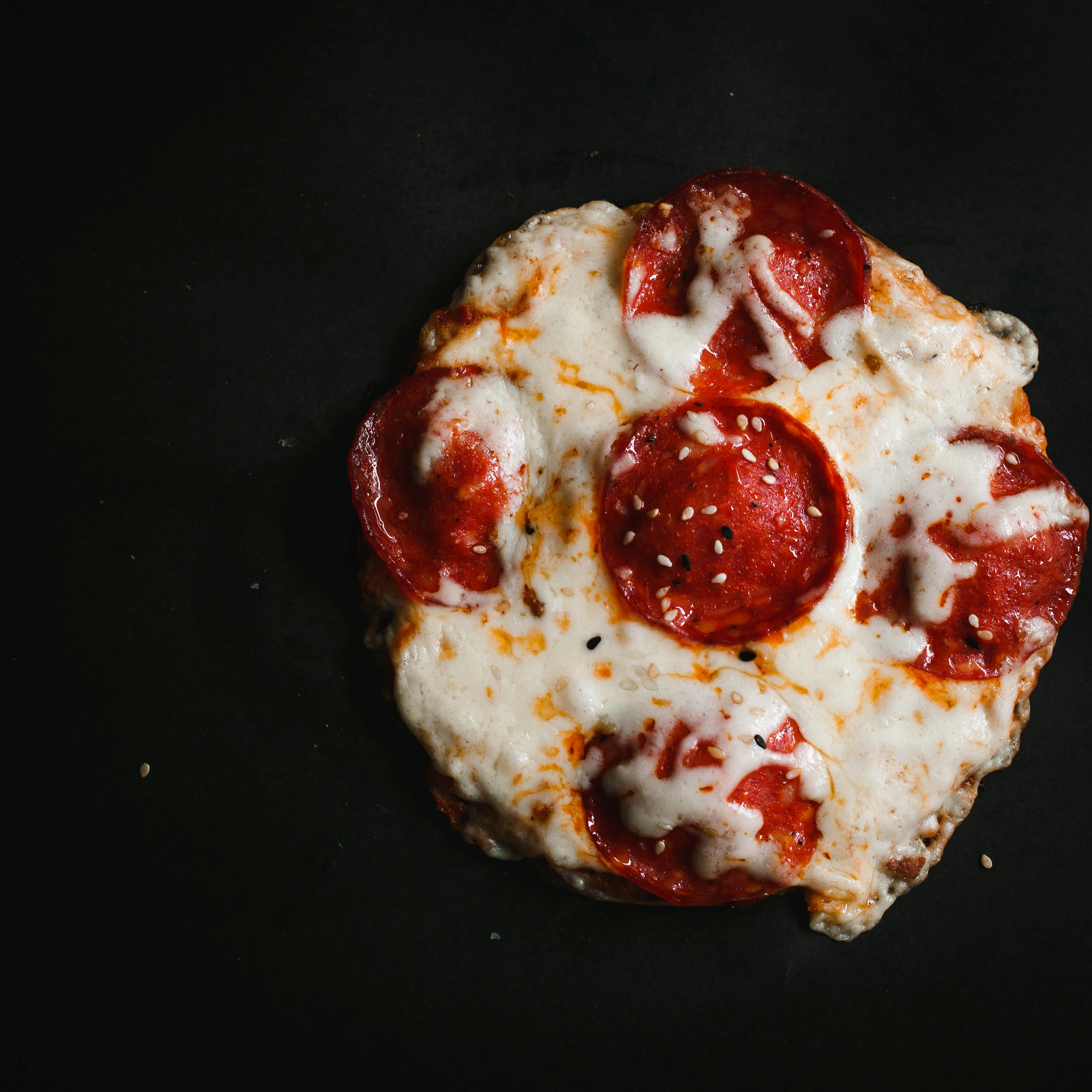Mouthwatering pepperoni pizza with melted cheese on a black backdrop. Perfect for food enthusiasts.
