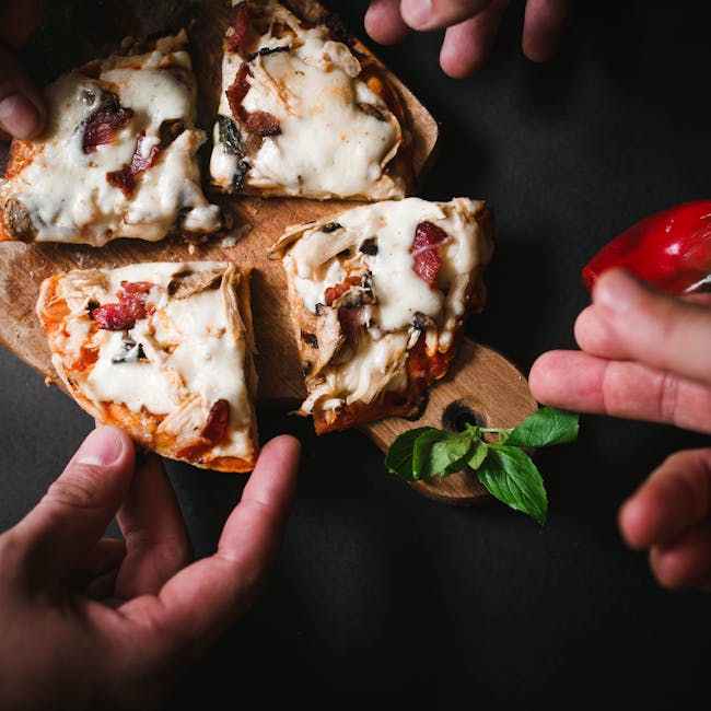 Top view of hands reaching for sliced mozzarella pizza on rustic wooden board with basil leaves.