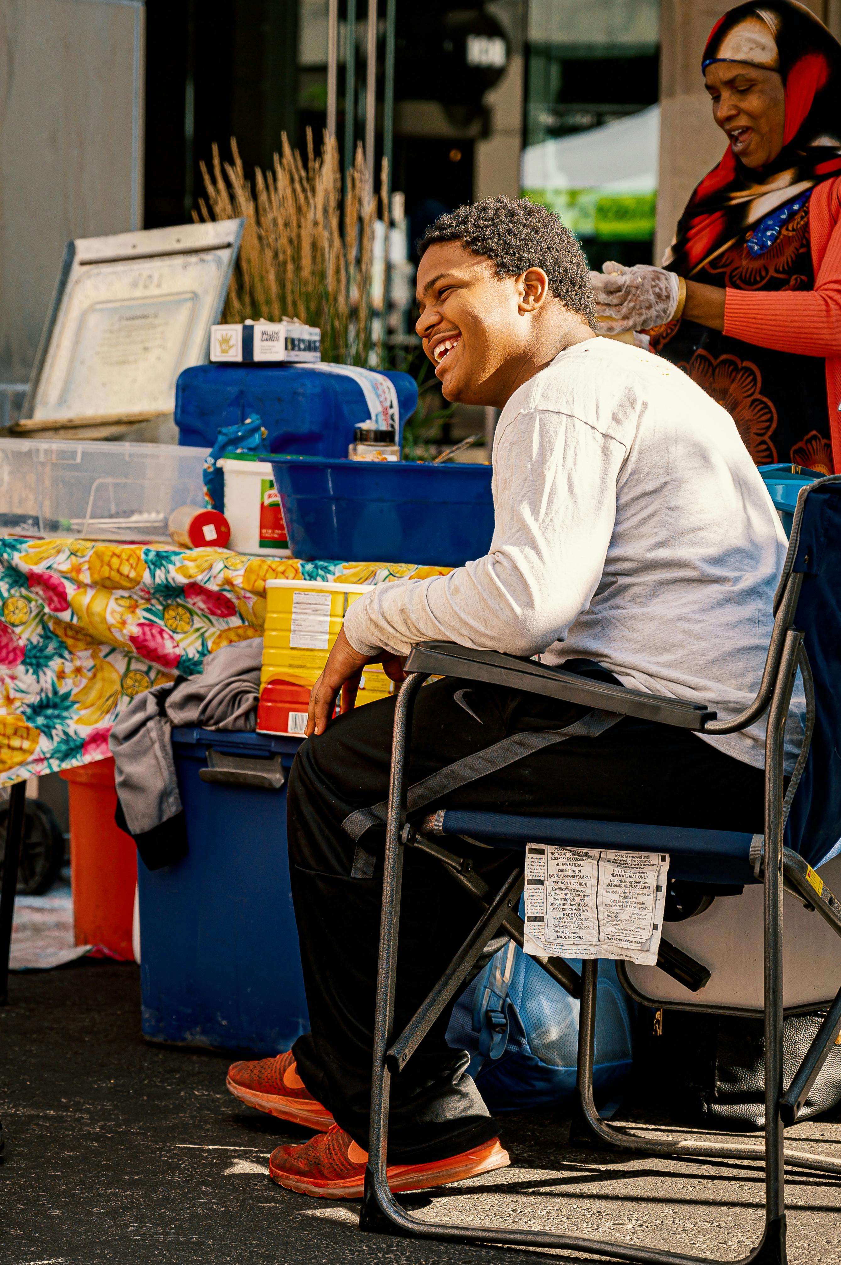 一个年轻人坐在充满活力的街头市场，微笑着感受城市时刻