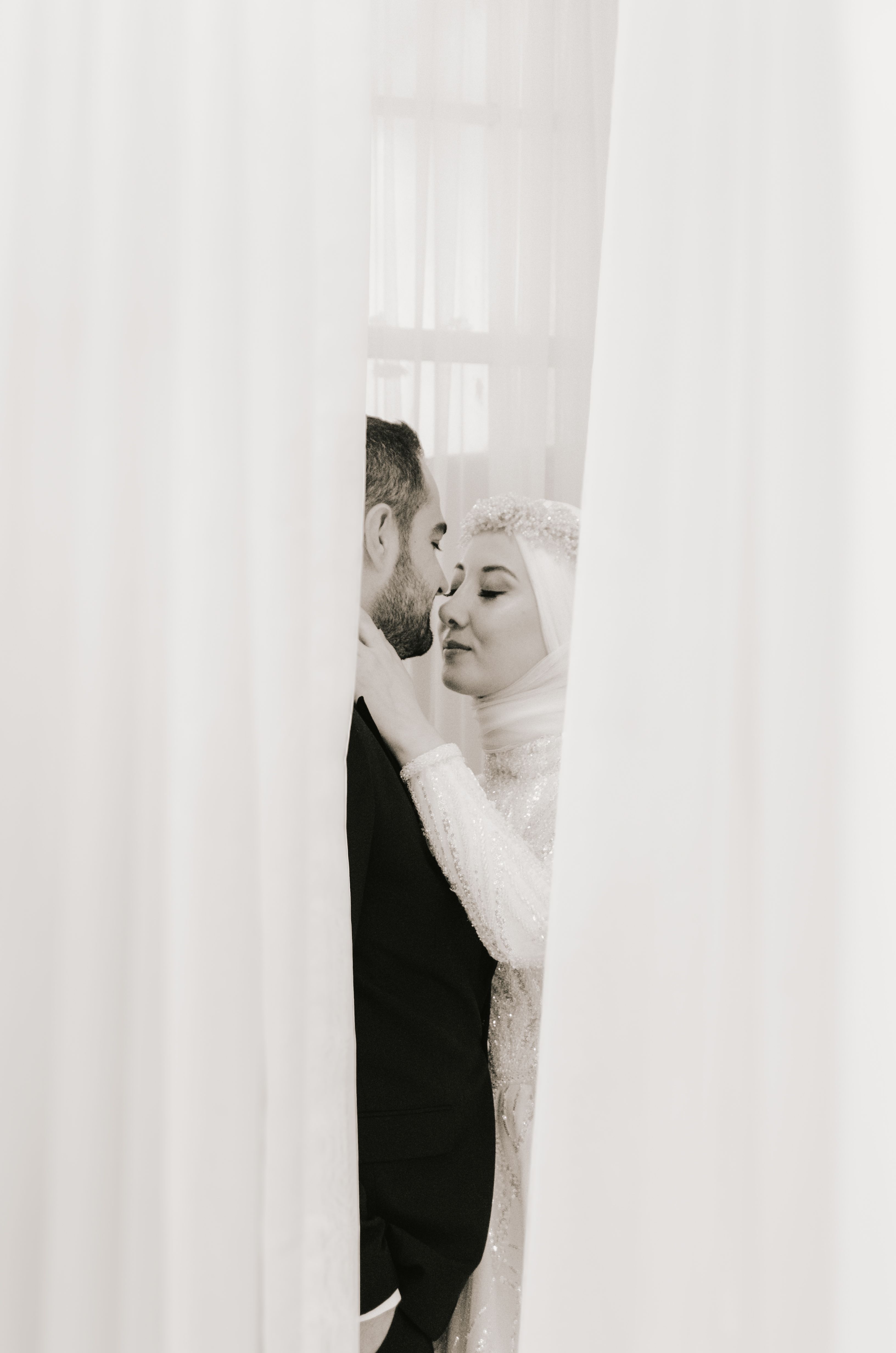 A bride and groom kissing in front of a curtain · Free Stock Photo