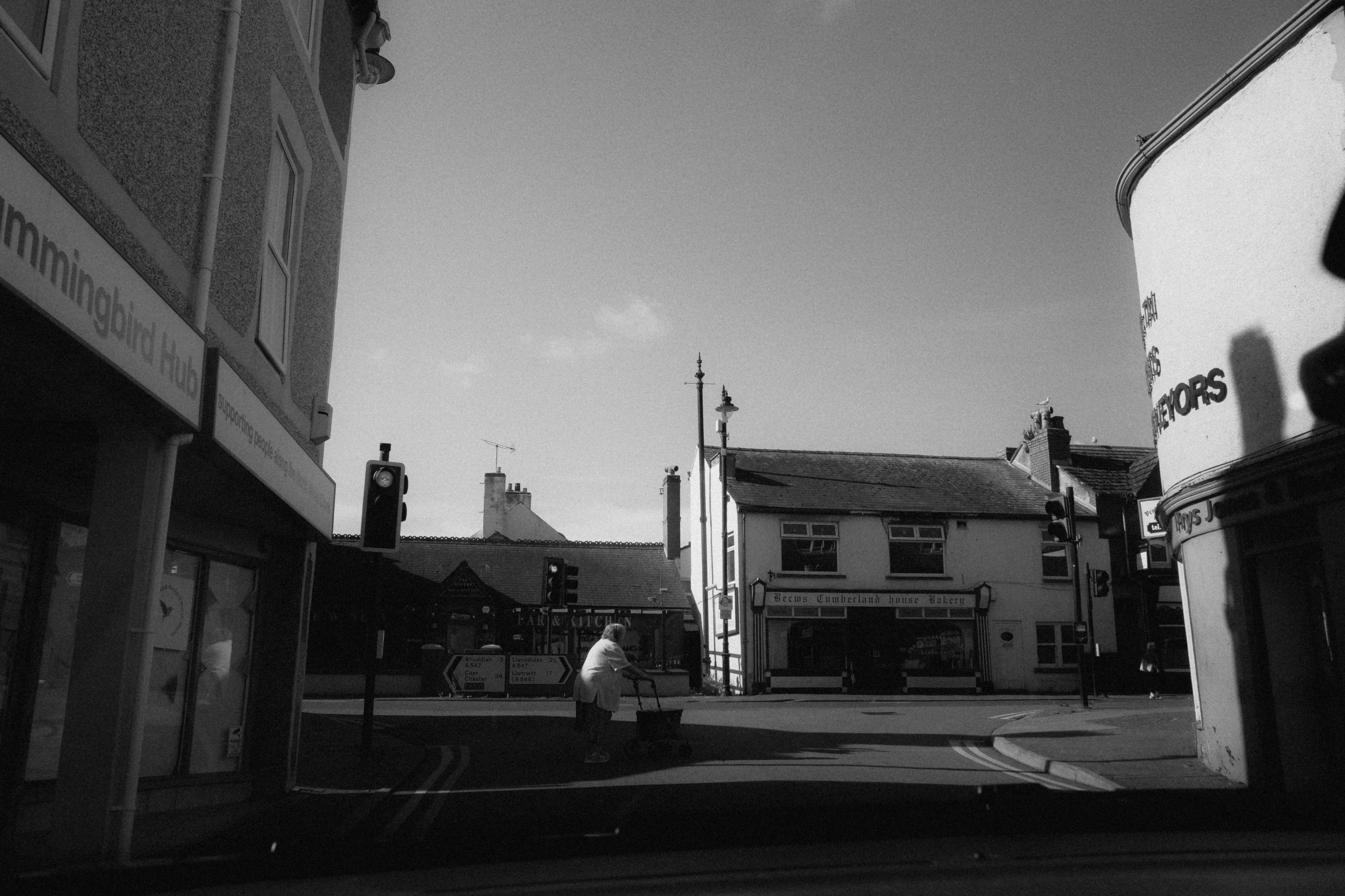 Black and white city street scene featuring a pedestrian crossing amidst historic buildings.