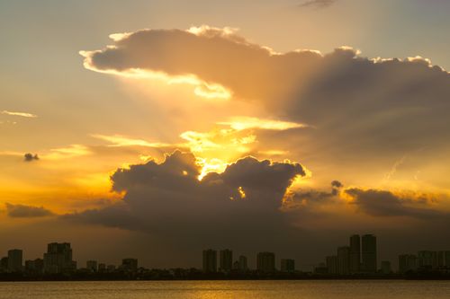 Free Stunning sunset over urban skyline with dramatic clouds and golden hues. Stock Photo