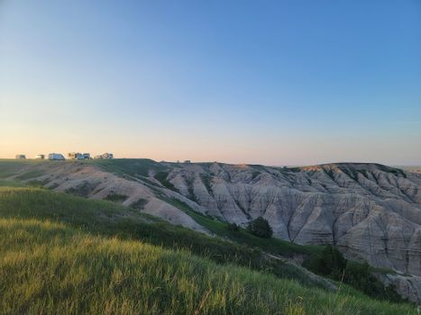 Dramatic geological formations and grasslands in Badlands at sunset, showcasing a serene natural landscape.