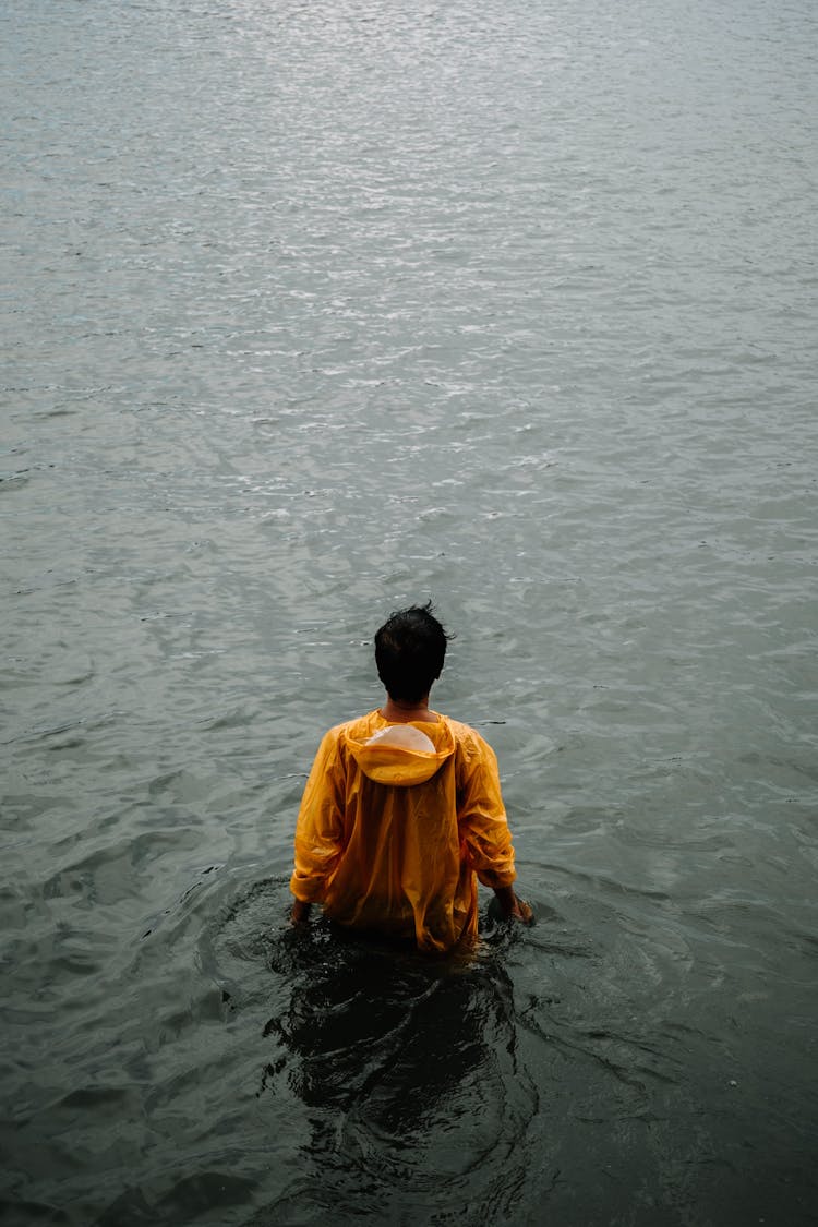 Back View Of Man Wearing Yellow Hoodie Standing In The Water