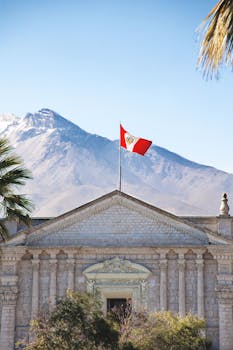 Colonial architecture in Arequipa, Peru, with Peruvian flag and Andes background.