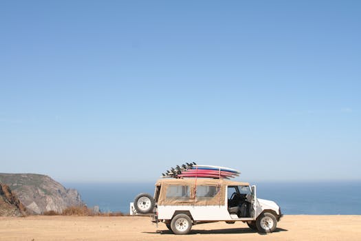 一辆装满冲浪板的吉普车停在风景秀丽的海洋悬崖上，天空晴朗