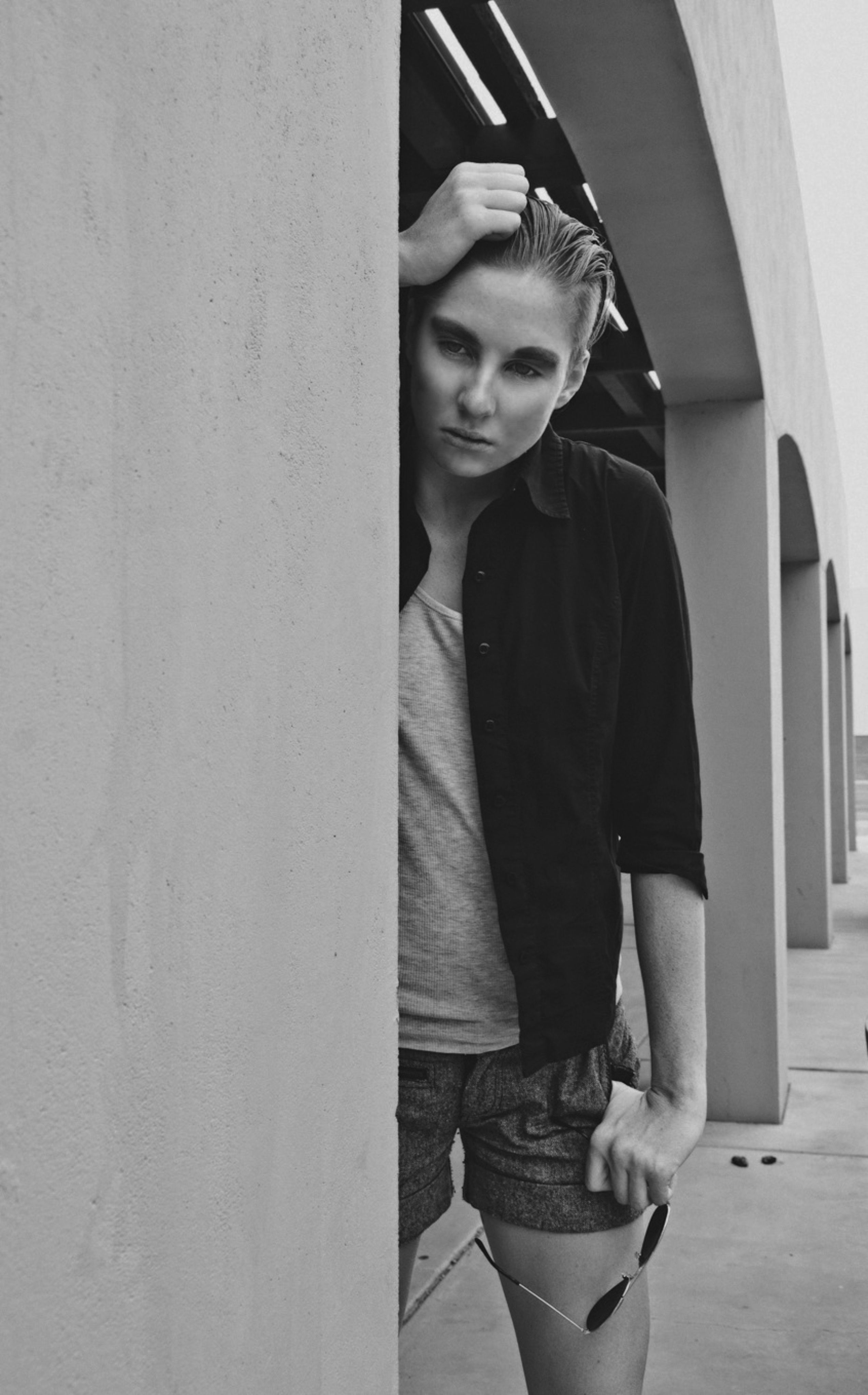 A woman leaning against a wall with her hand on her hip · Free Stock Photo