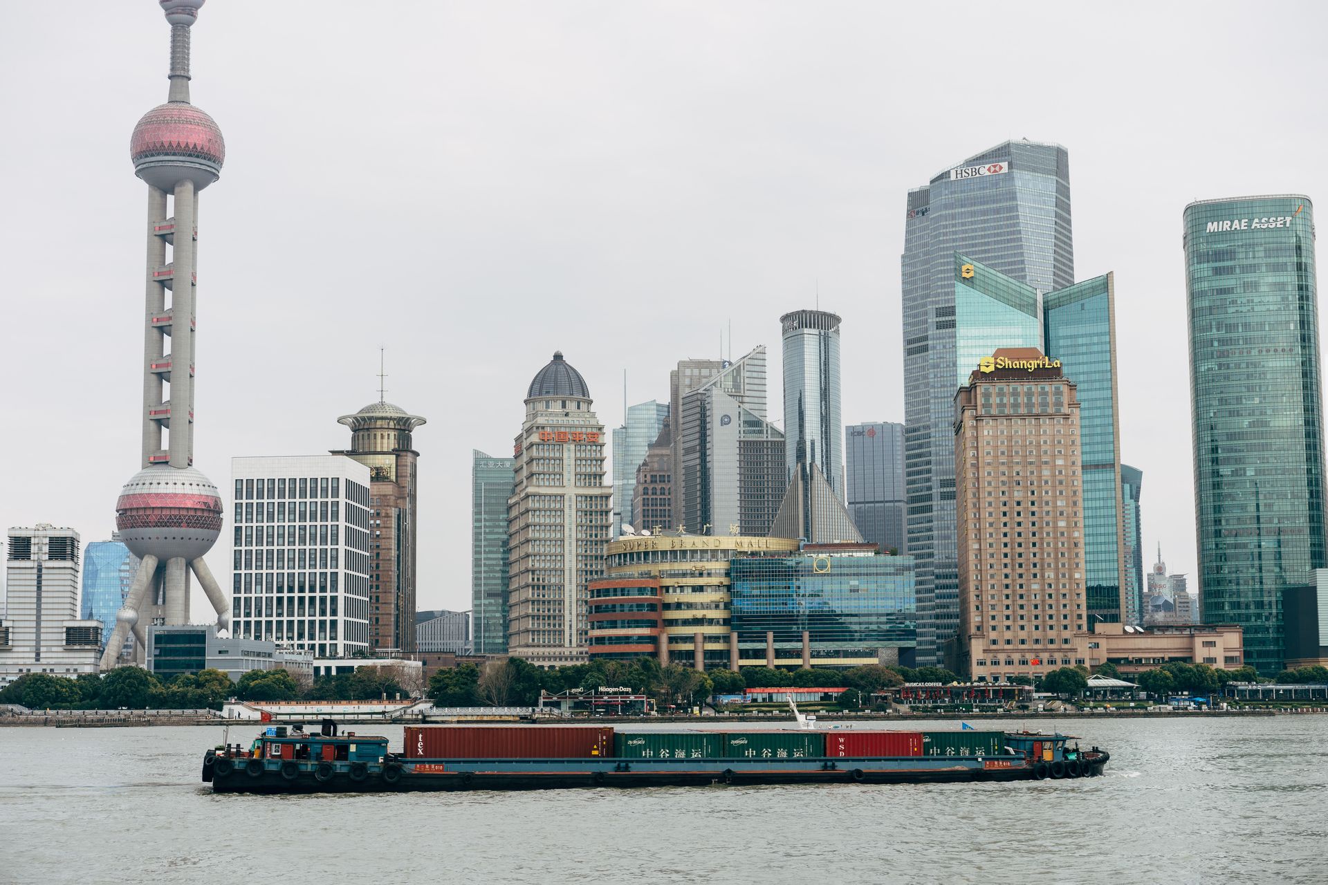 Panoramic view of Shanghai skyscrapers and a cargo boat on Huangpu River, capturing the city's modern architecture.