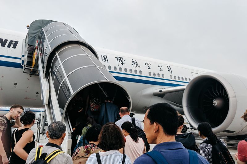A group of people boarding an airplane via a jet bridge at Beijing Airport, China.