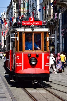 The classic red tram moves through bustling Istiklal Street in Istanbul, capturing the essence of city life.