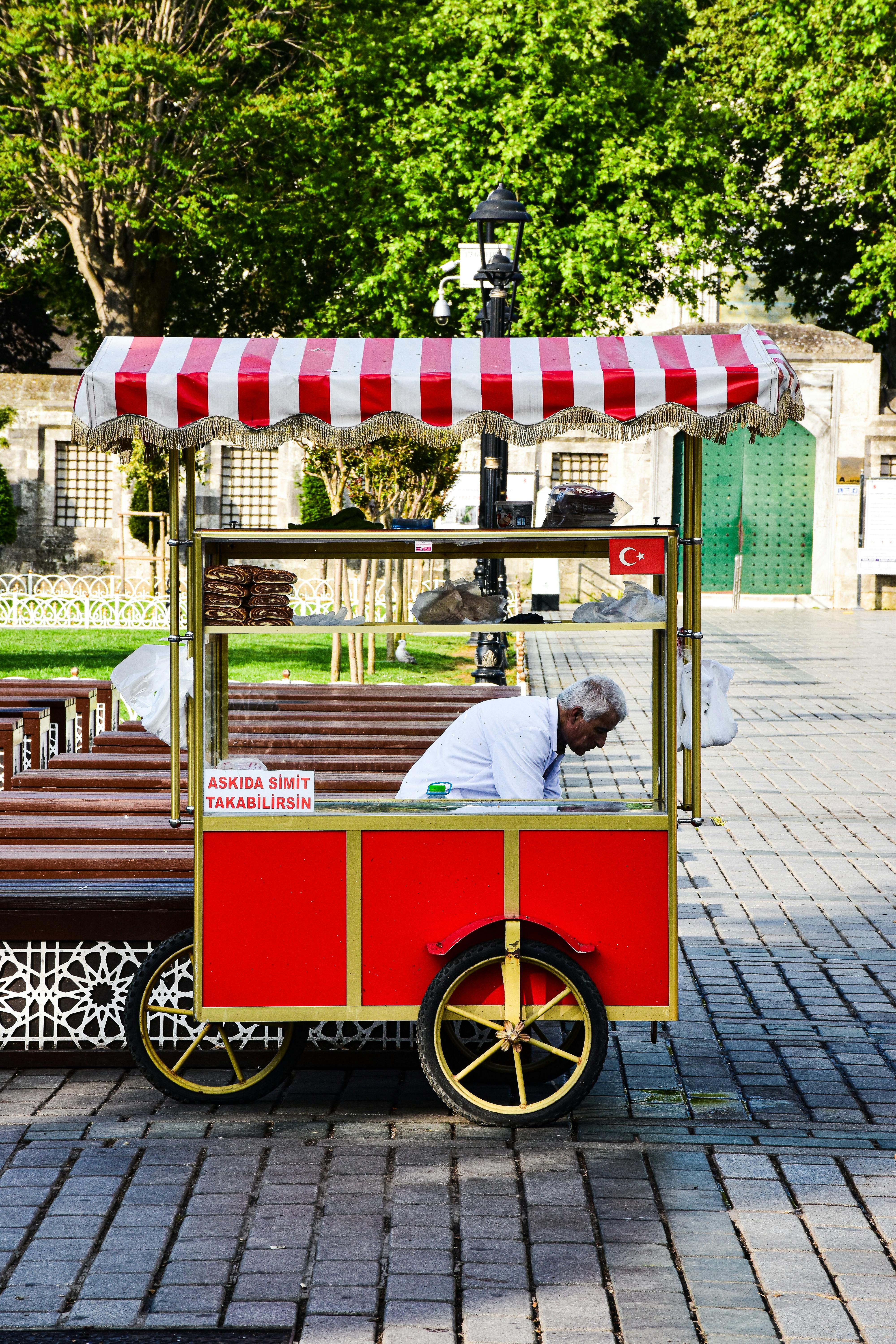 a man selling food on a cart in a park