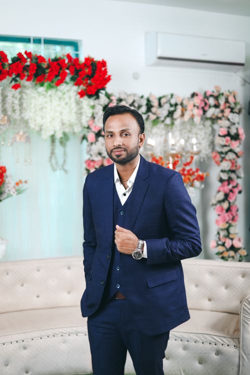 Free Handsome Indian groom wearing formal blue suit at a wedding ceremony with floral backdrop. Stock Photo