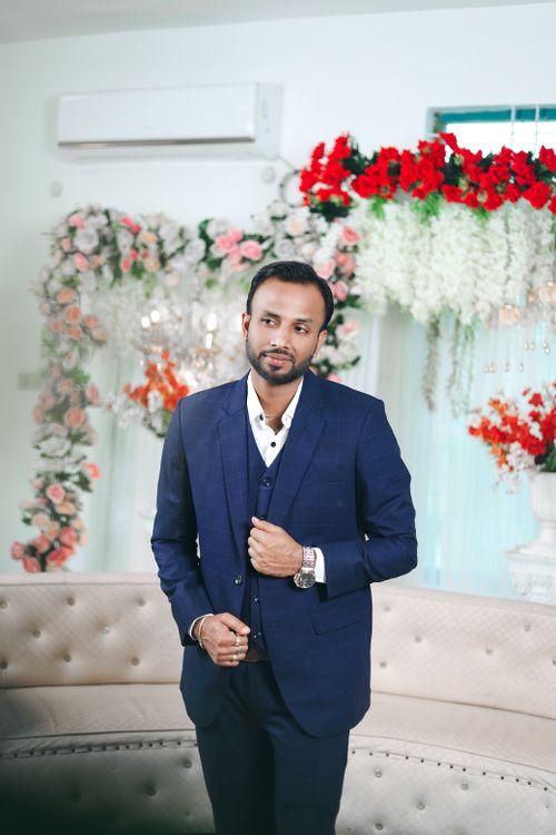 Free Stylishly dressed groom in a blue suit poses at an indoor Indian wedding ceremony. Stock Photo