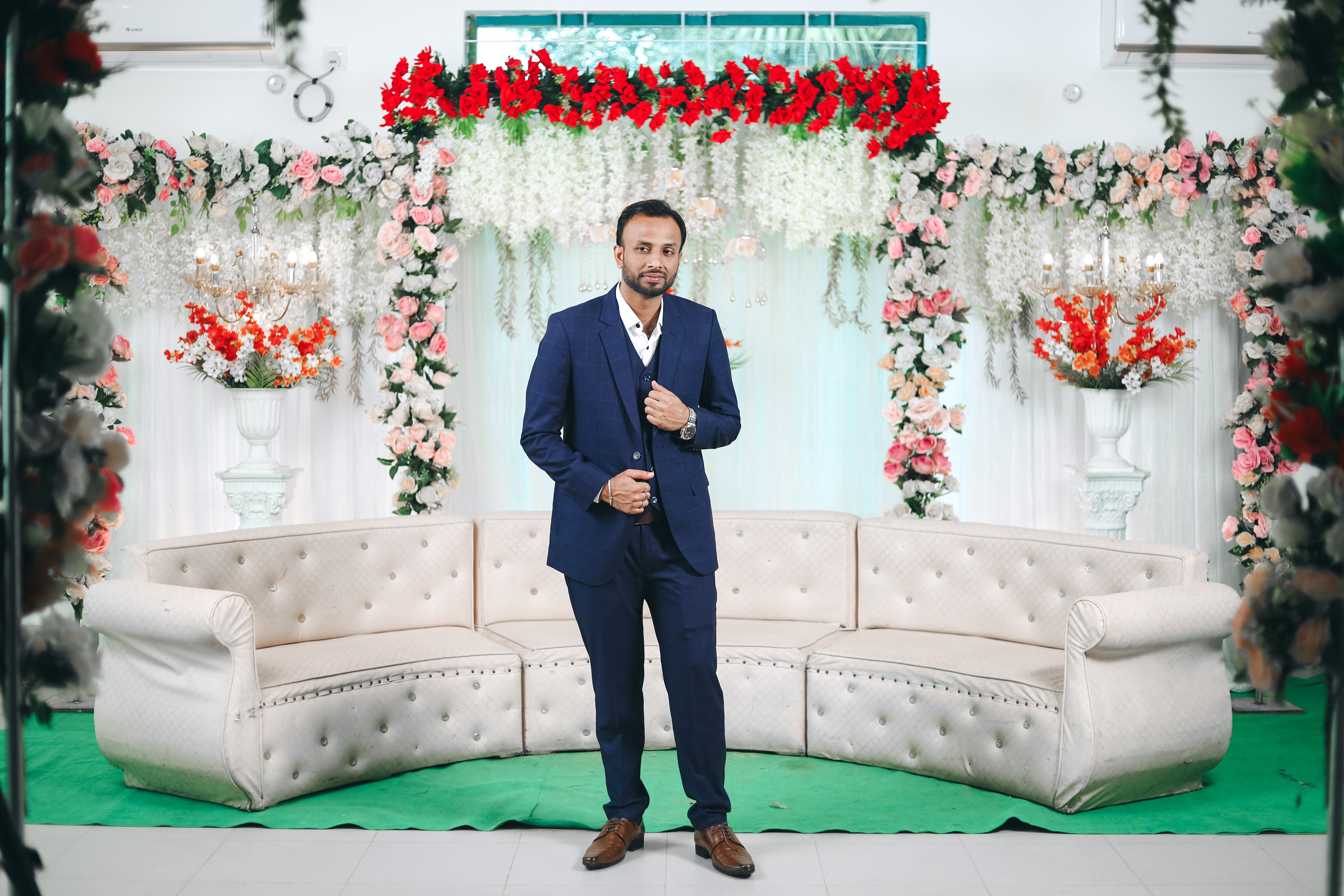 A man in a suit standing in front of a floral backdrop · Free Stock Photo