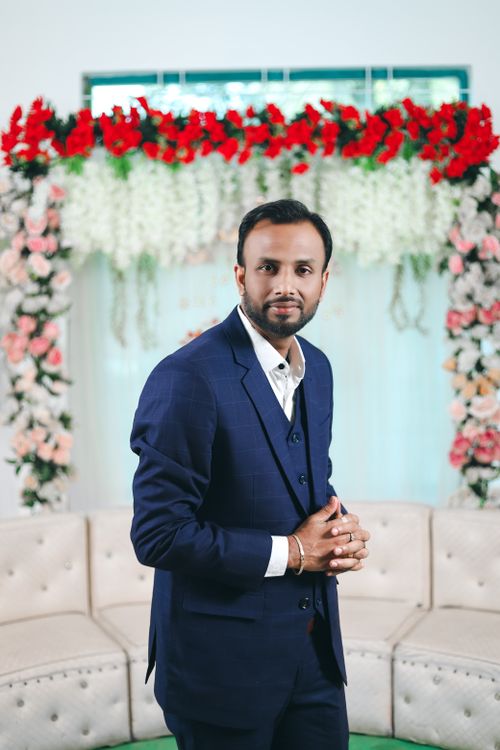 Free A man in formal attire posing confidently at beautifully decorated indoor wedding venue. Stock Photo