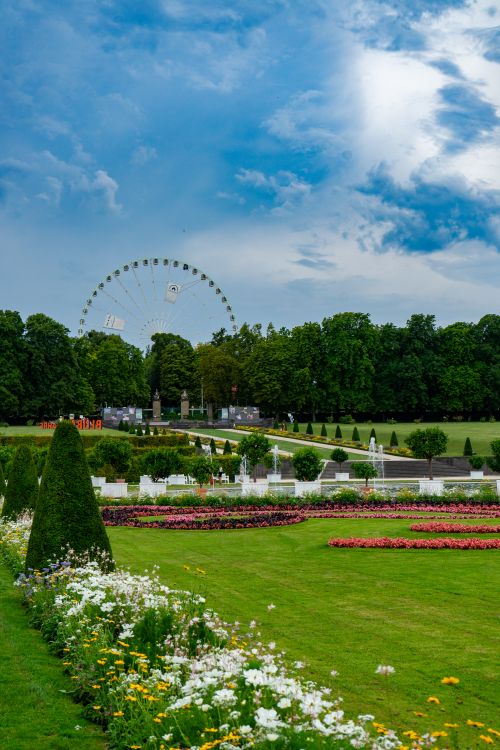Free Beautiful Ludwigsburg park scene with lush gardens and a Ferris wheel on a sunny day. Stock Photo
