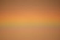 An orange and yellow sunset with a plane in the sky