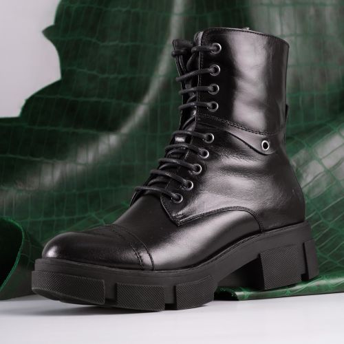 Free High angle view of a shiny black leather combat boot with green background. Stock Photo