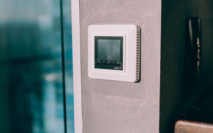 Smart thermostat mounted on a concrete wall, reflecting modern interior design with natural light.