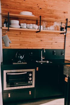 Contemporary black and wood kitchenette with open shelves and appliances.