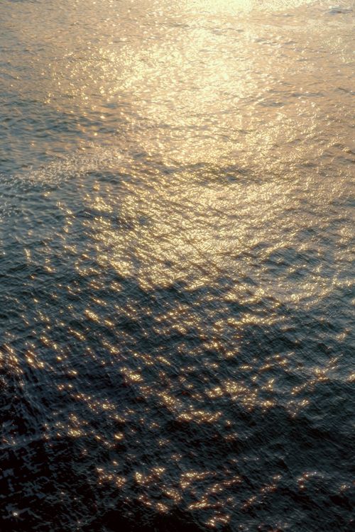 Free Beautiful golden sunset casting light reflections on tranquil ocean waves. Stock Photo