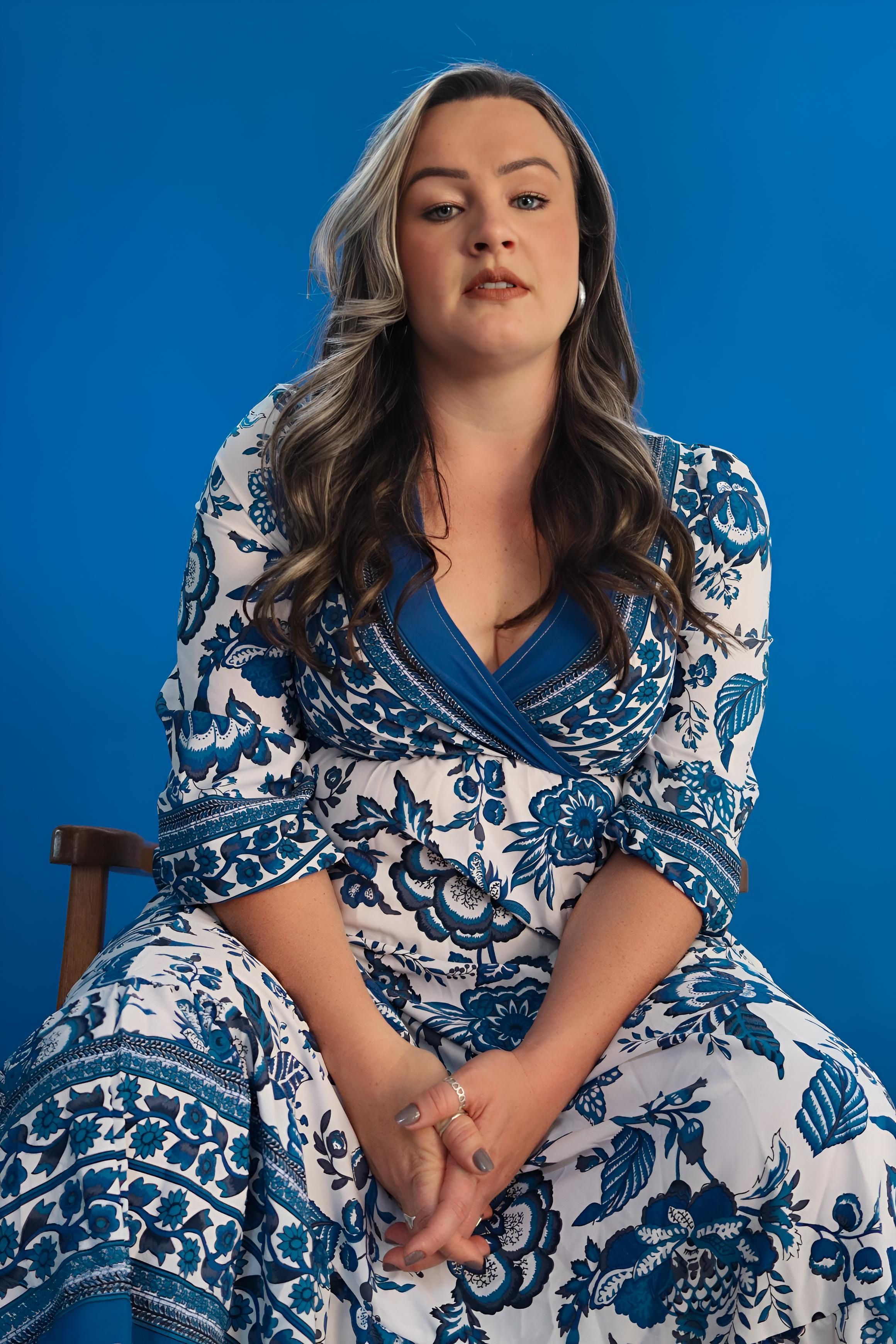 A woman in a blue and white dress sitting on a chair · Free Stock Photo