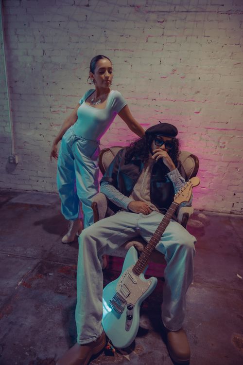 Free A trendy pair poses with an electric guitar in a moody indoor setting. Stock Photo